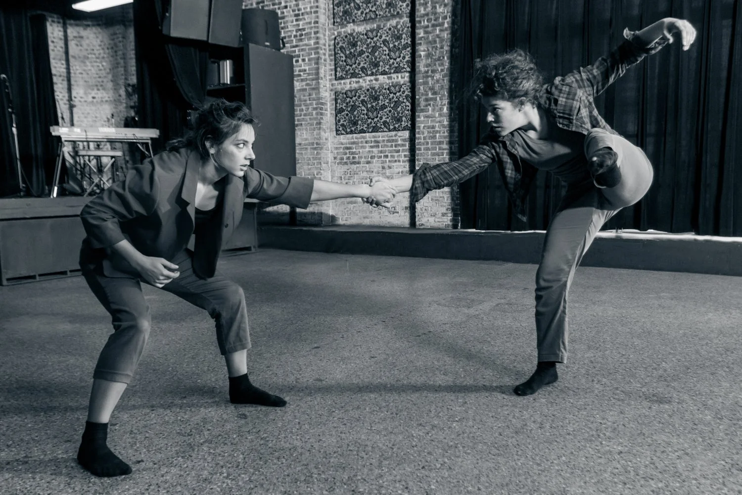 Anna and Leah dance together on the floor at Motorco. Anna shares weight with Leah while Leah is on one leg.