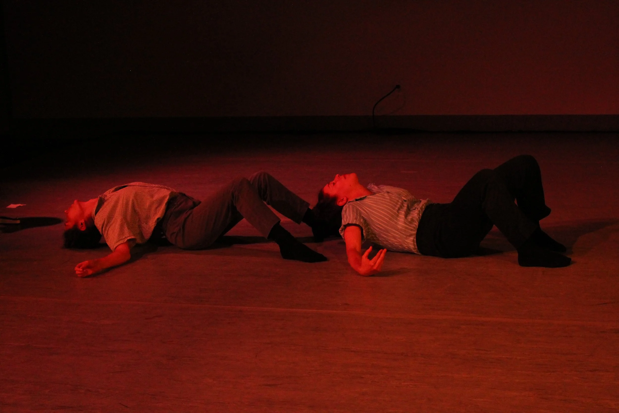 Leah and Anna lie on the ground in a birthing-like position.