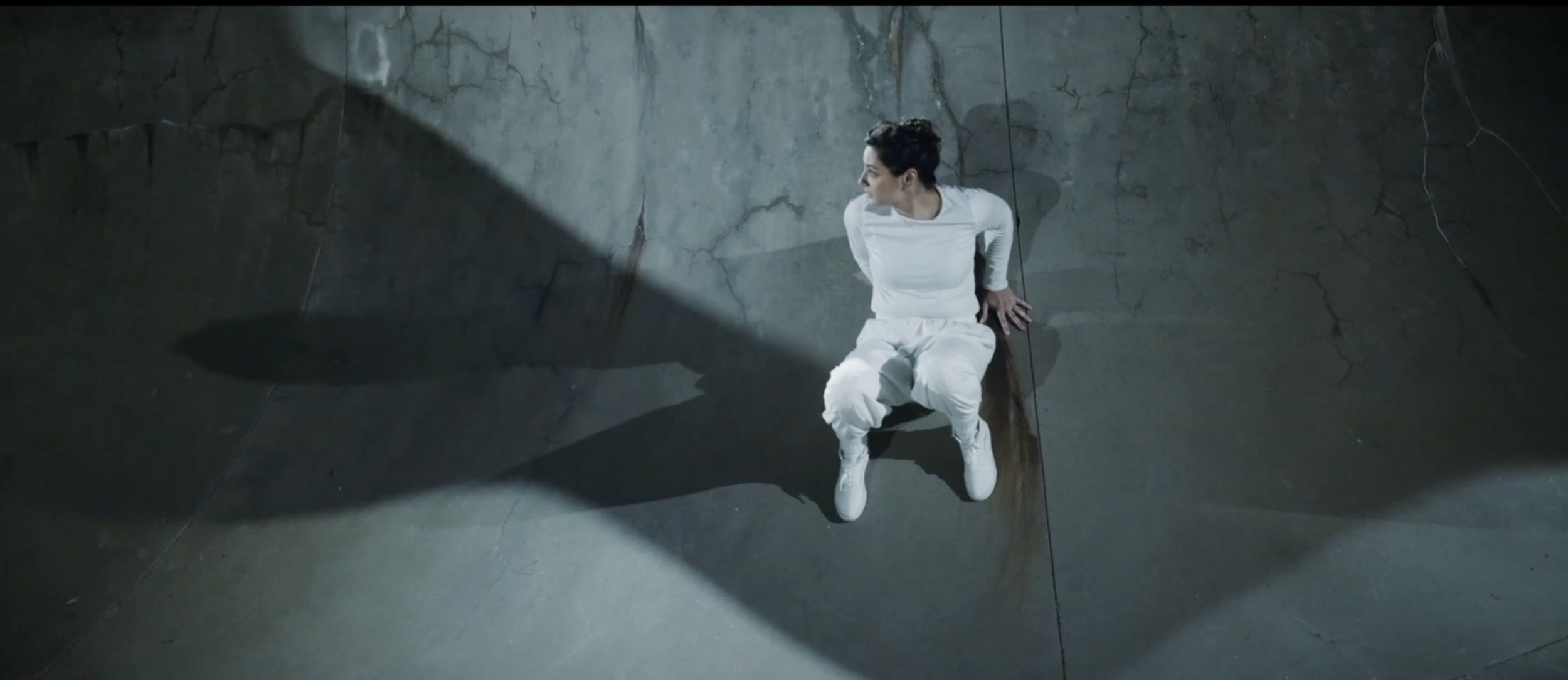 Anna wears all white. She clings to the edge of a skate park bowl.