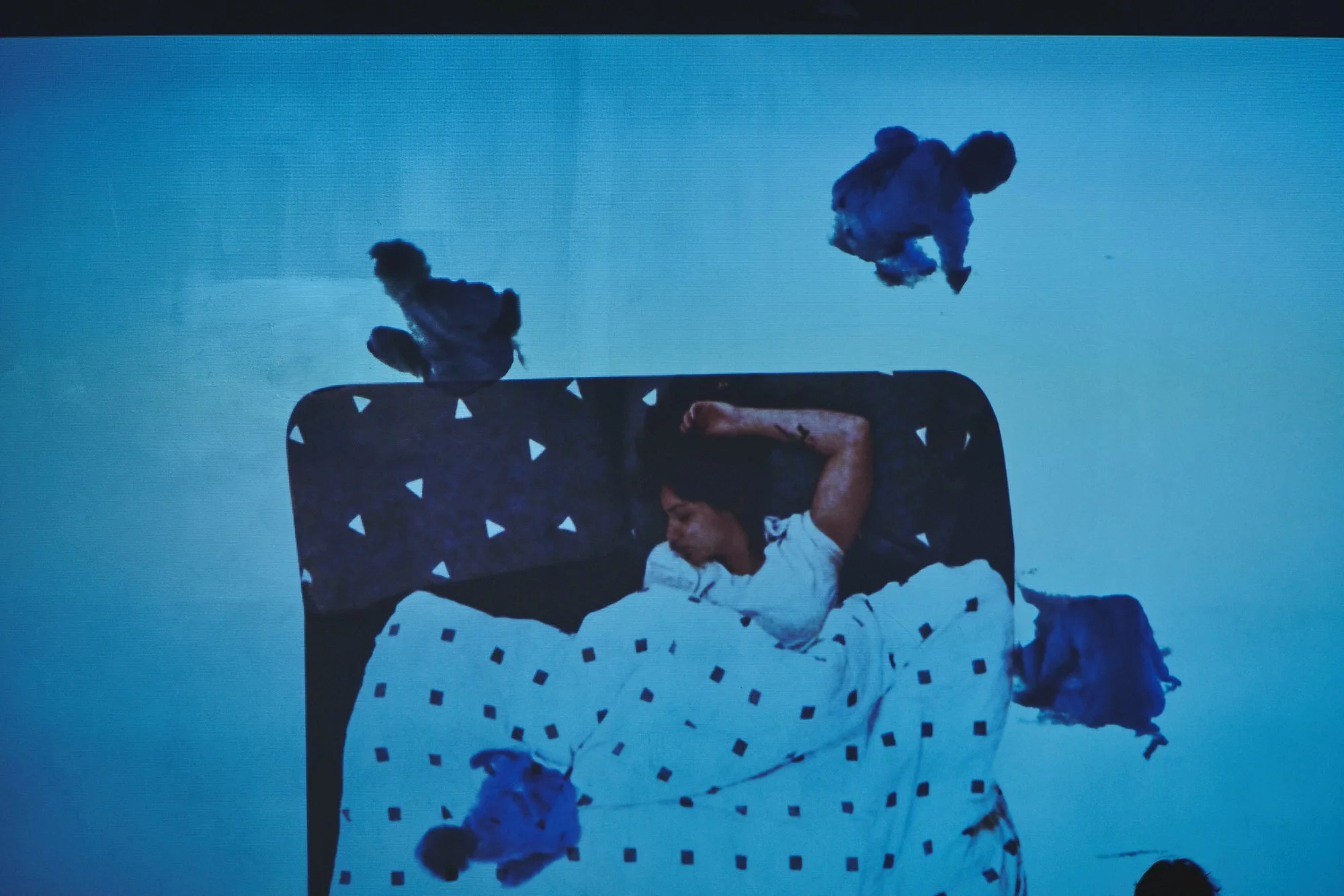 A projection of Anna tossing and turning in bed. Four dancers swirl around her.