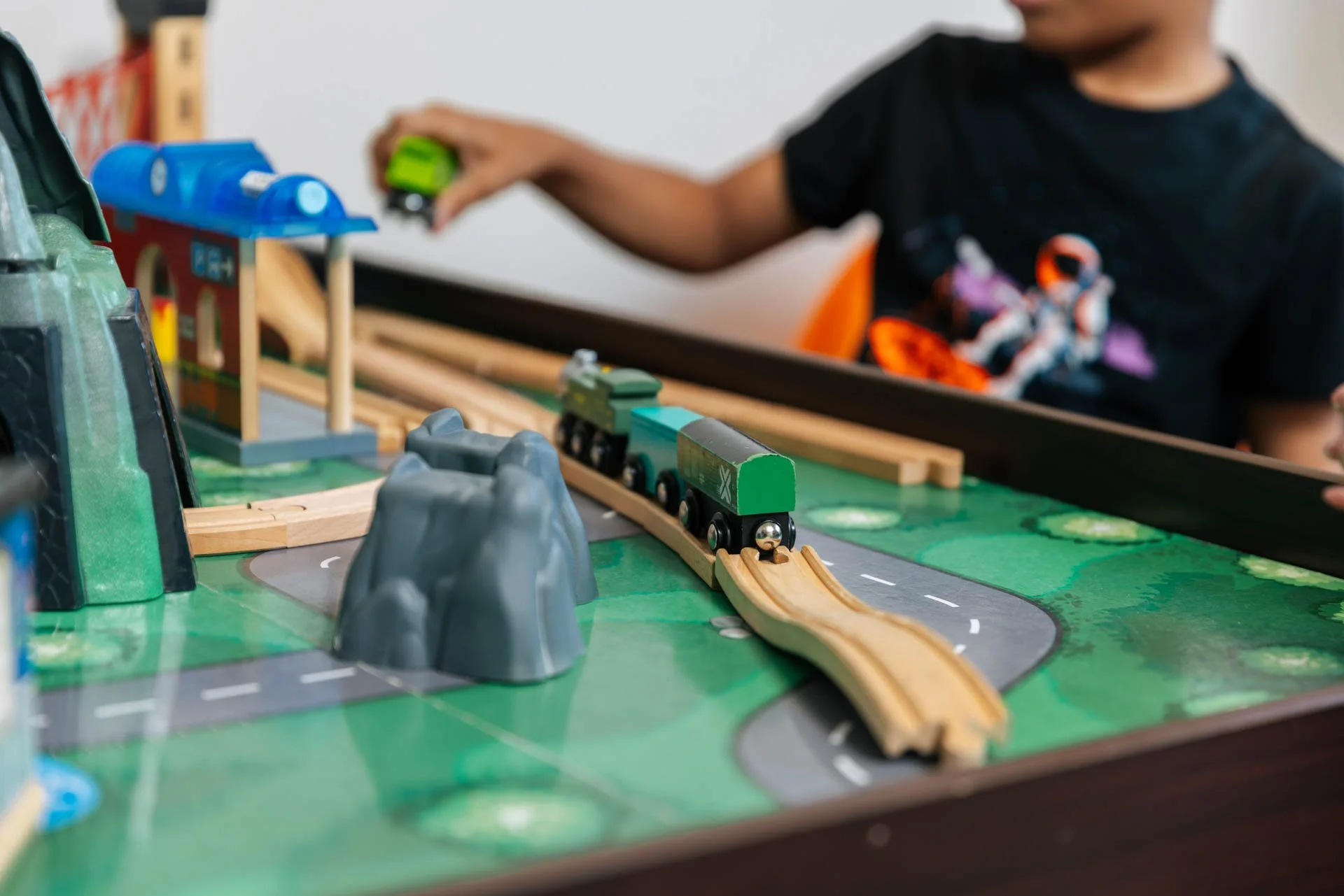 Children playing with a wooden train set on a tabletop.