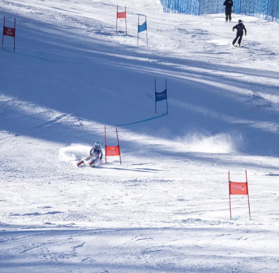 A skier navigating a slalom course on snow-covered slopes during a race, with gates marked by red and blue flags.