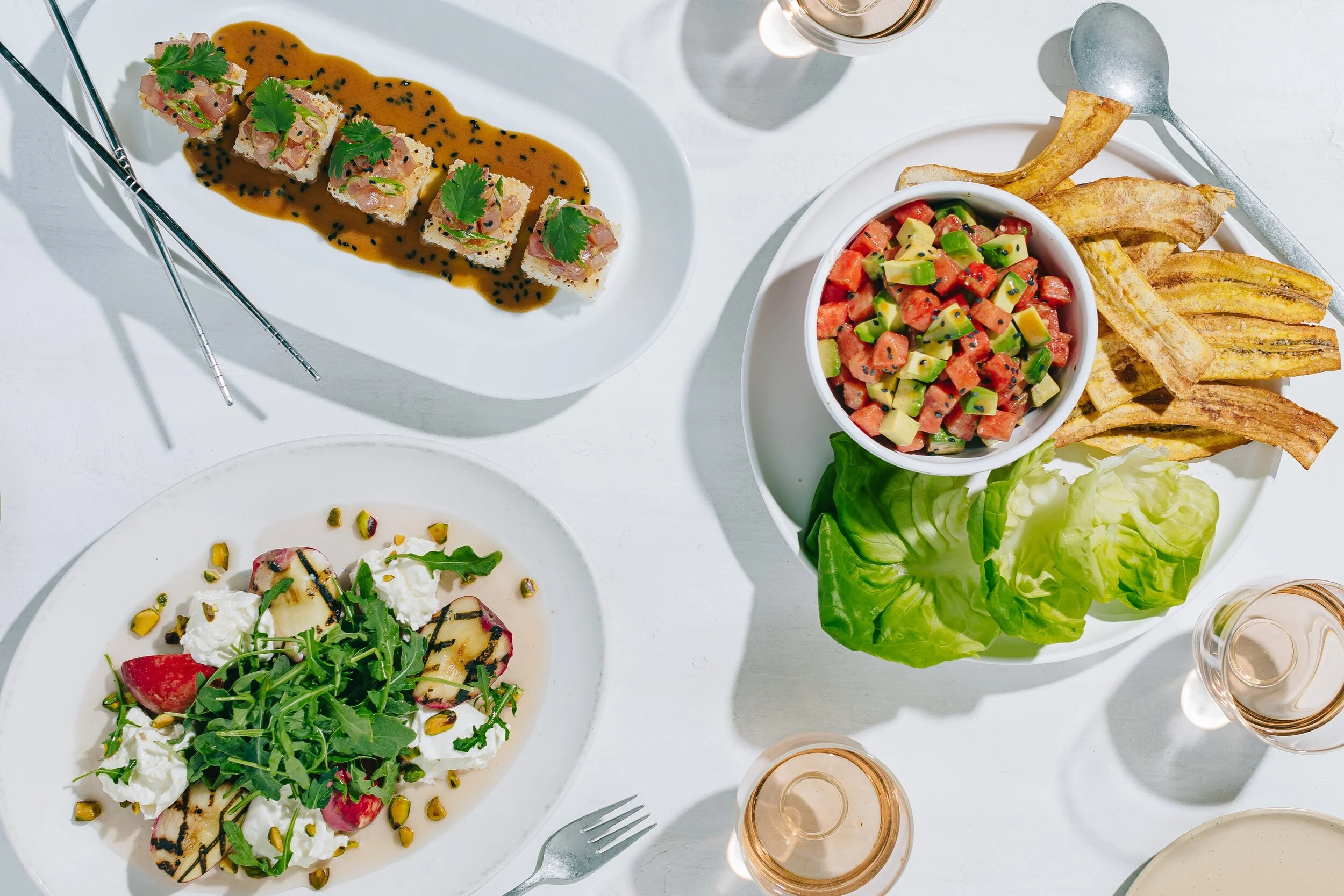 Photo art direction for True Food Kitchen by Brianna Vannelli of B Creative. Image is a top down shot of True Food's summer meanu featuring poke bowl, crispy tuna, and a salad with rosé wine.