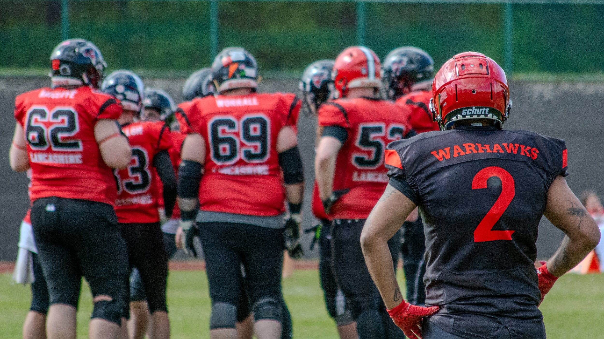 American football players on the field, some with helmets and uniforms, during a game or practice.