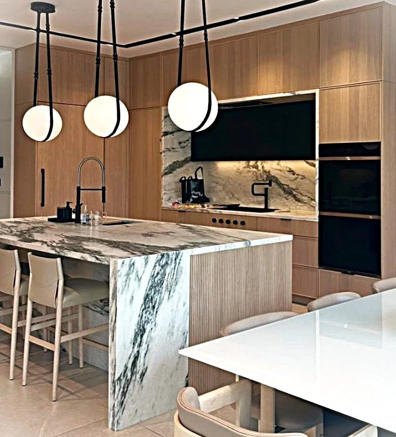 Modern kitchen with marble island, wooden cabinets, black appliances, and pendant lights.