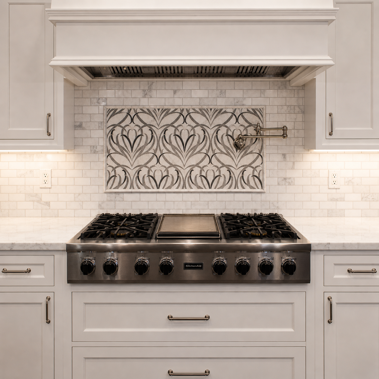 Kitchen with white cabinets, white marble countertop, stainless steel gas stove, decorative tile backsplash, and under-cabinet lighting.