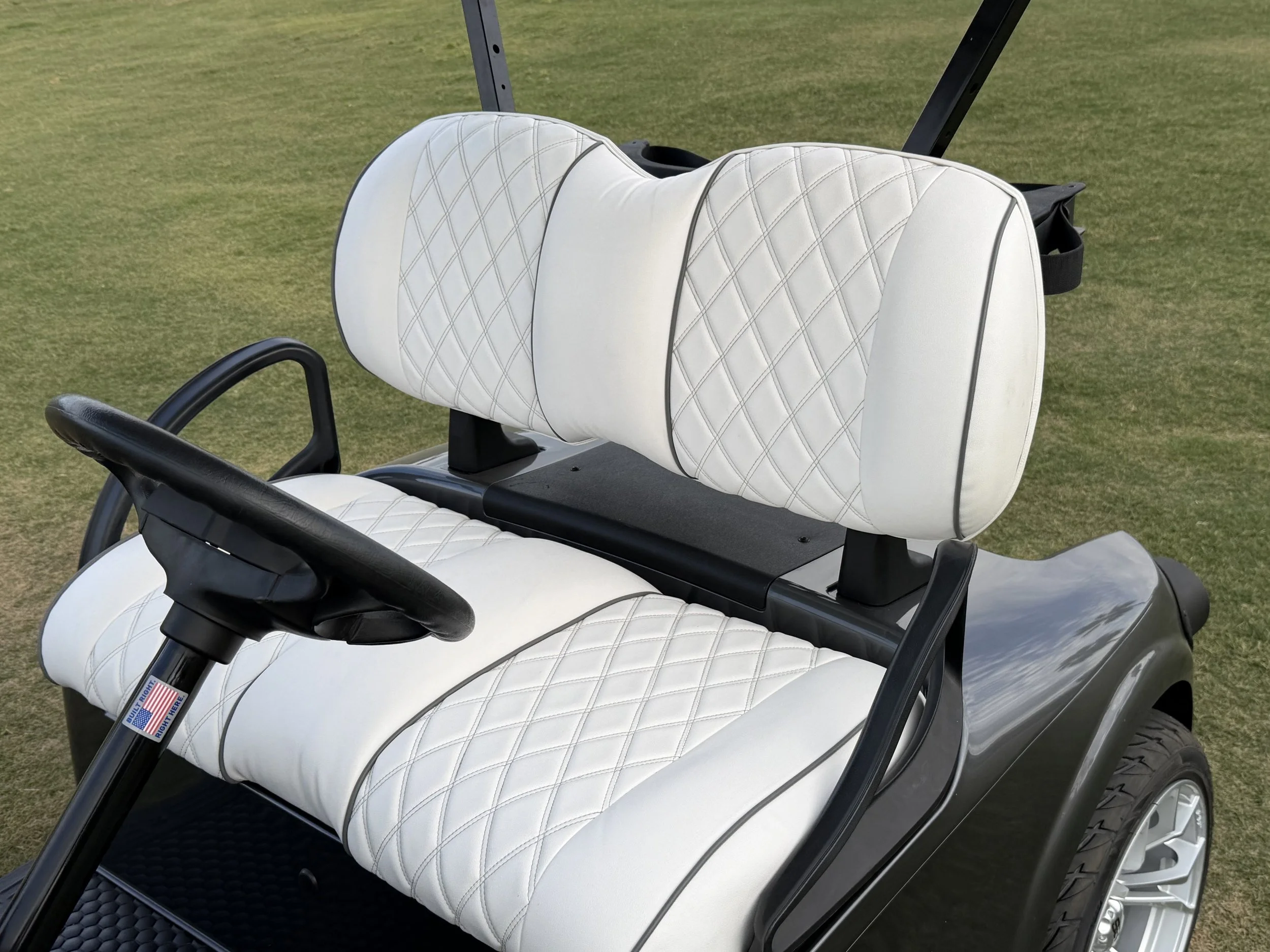 Close-up of two white golf cart seats with diamond stitching, set on a golf course with green grass in the background. Rio Verde Golf Cart, Fountain Hills, Scottsdale Golf Cart, Scottsdale golf cart repair