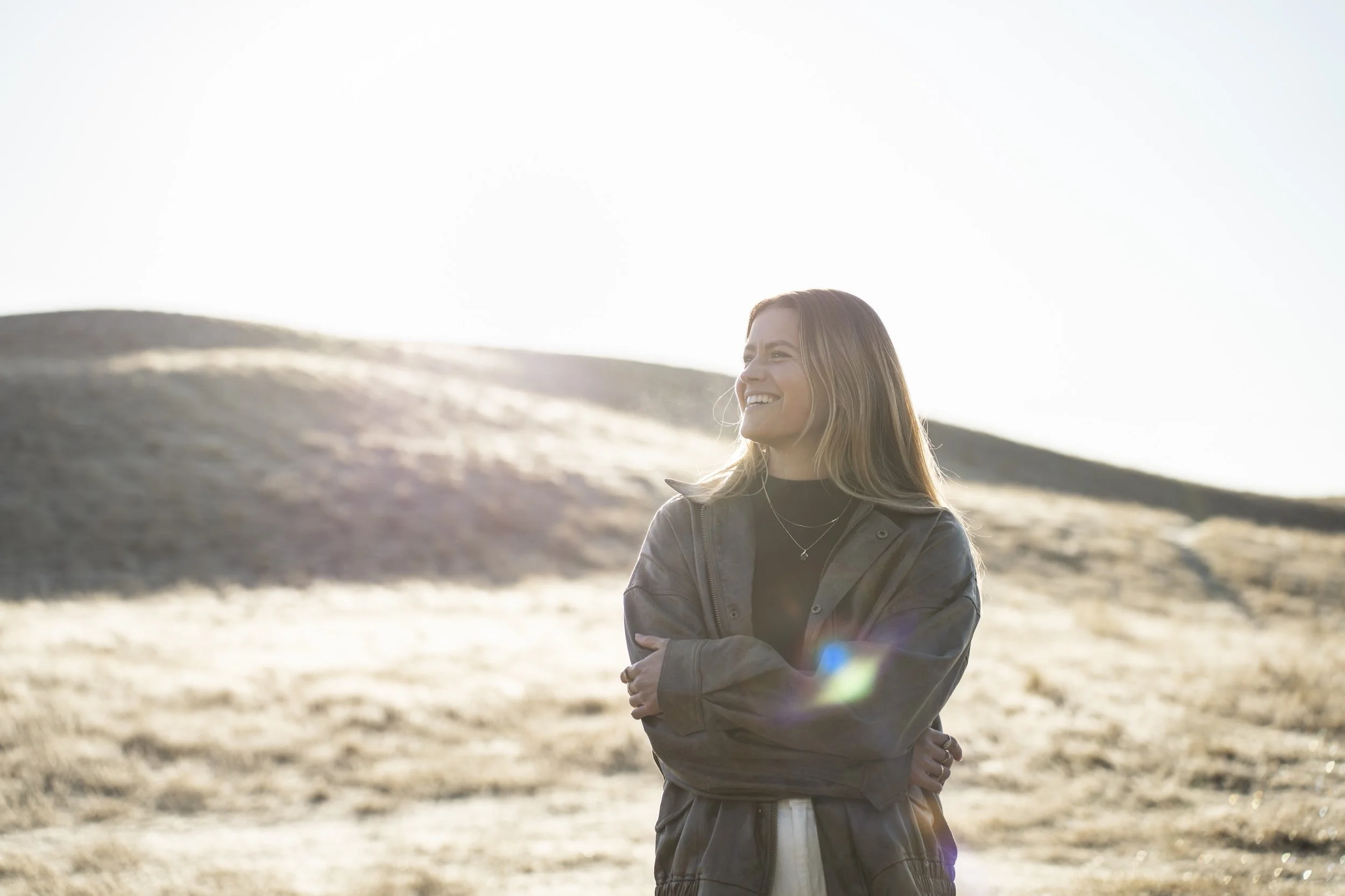 Kelsey Brownrigg standing in golden light on a hill top.