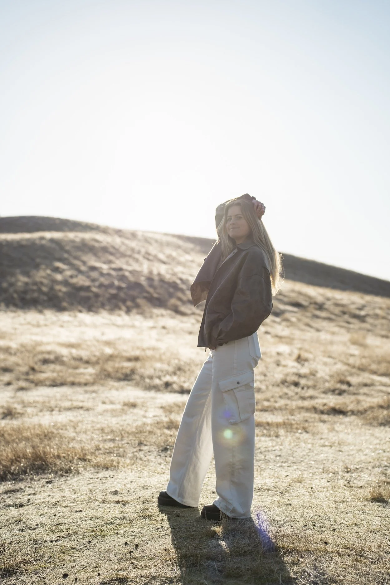 Kelsey - energy healer standing on a hill in bright light.