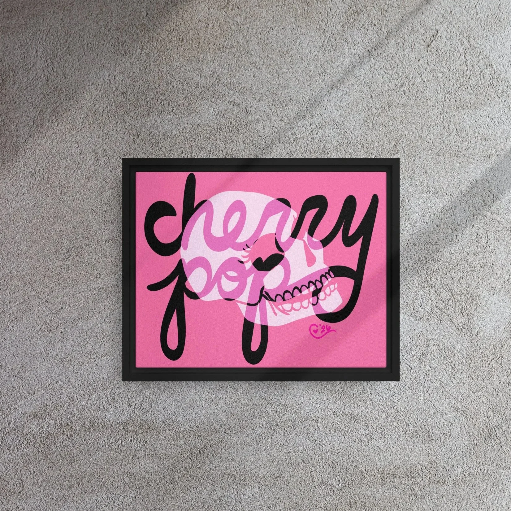 Pink framed art piece on a gray wall features black and white skull, overlayed with the words "cherry pop" written in black cursive.