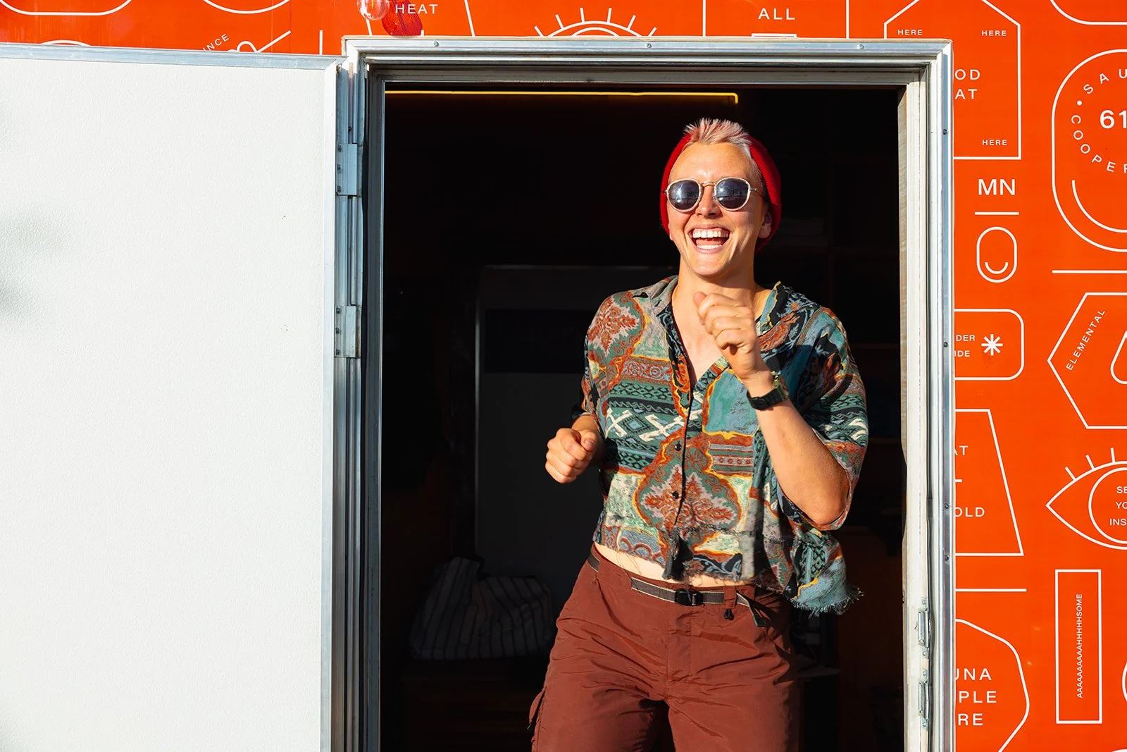 A woman smiling and running through a food truck window with a bright orange background and white instructional graphics.