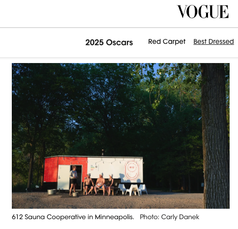 People sitting outside in front of a red and white sauna trailer in a wooded area.