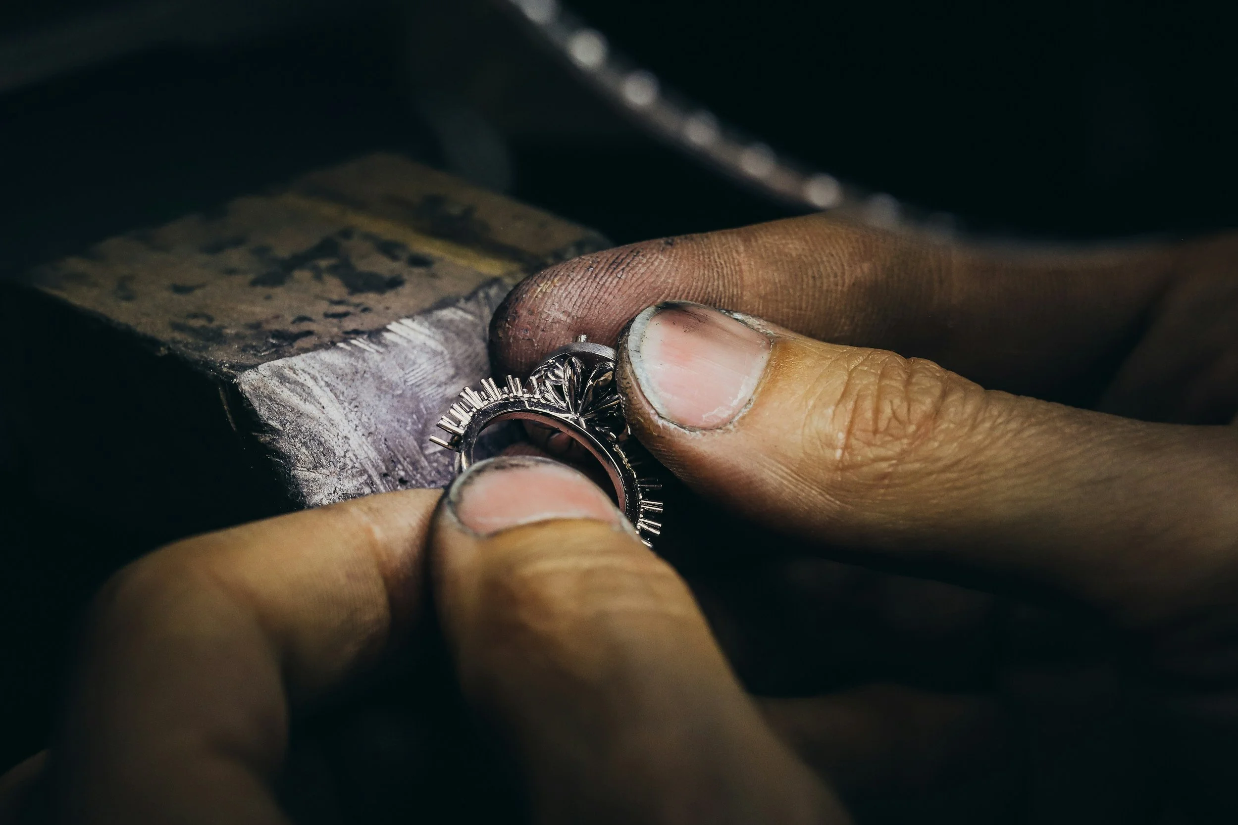 Mãos sujas de um artesão segurando um anel em um local de trabalho