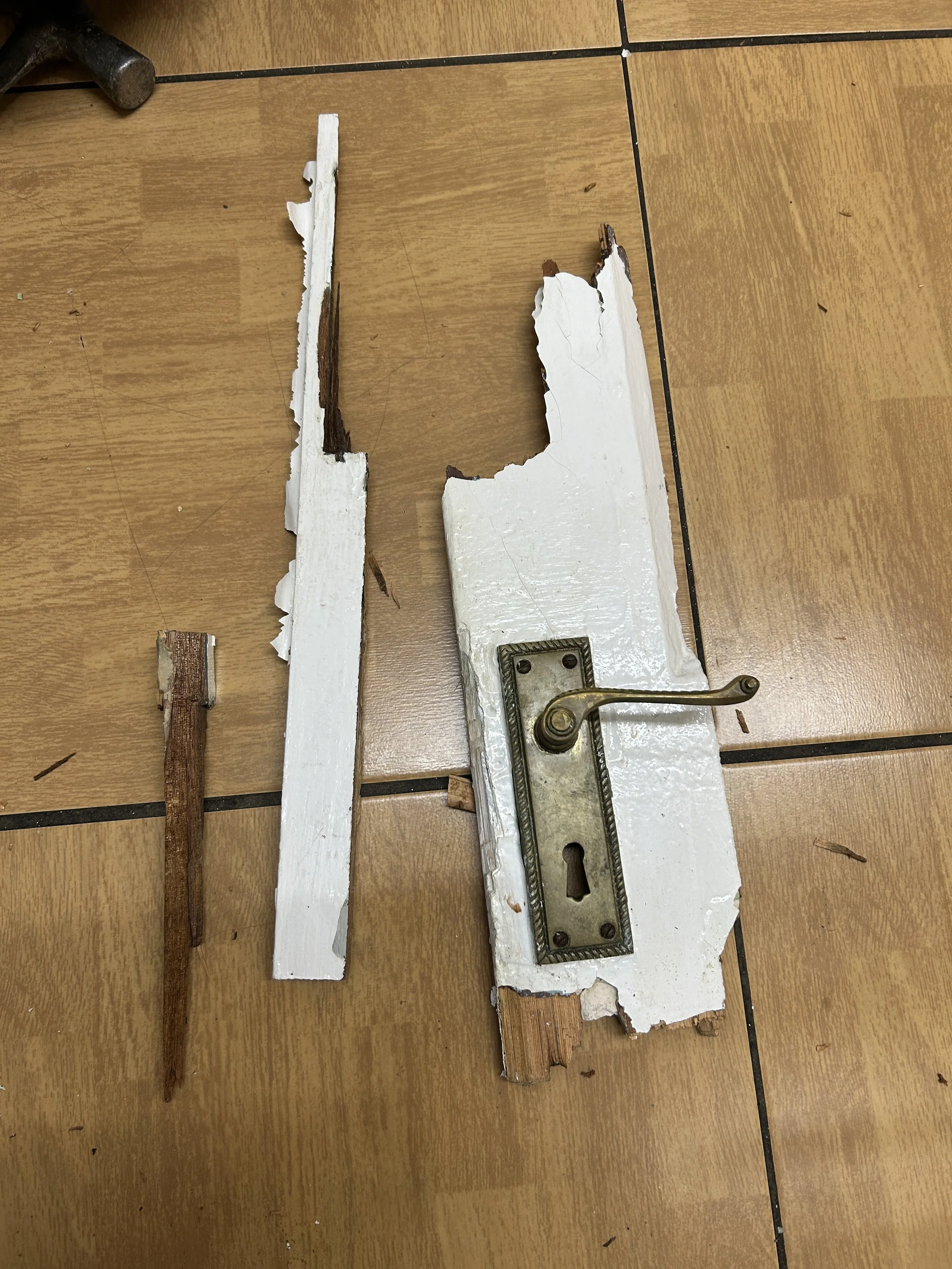 Broken wooden pieces and a metal latch on a wooden surface.