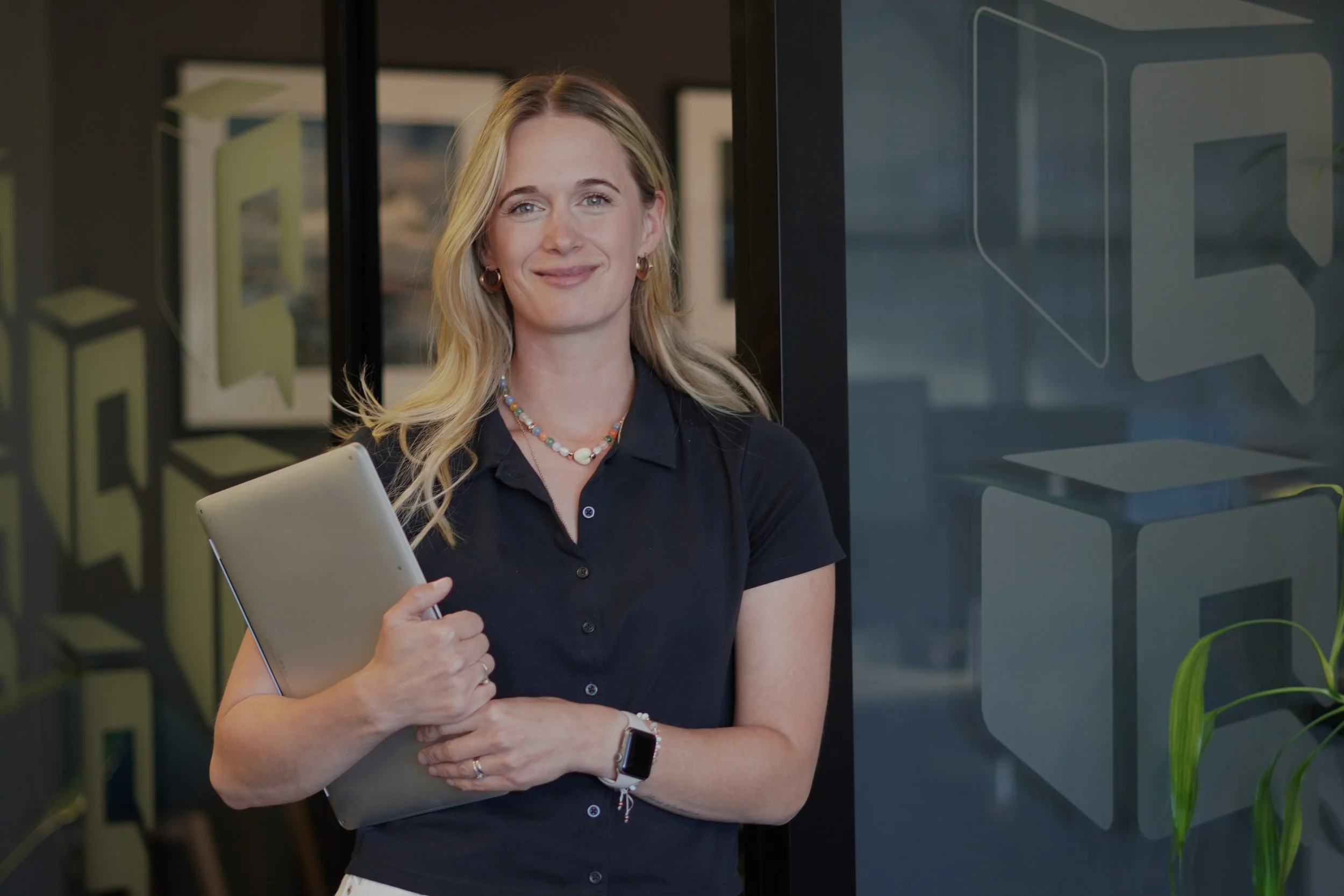 Smiling blonde professional holding a tablet in a modern office