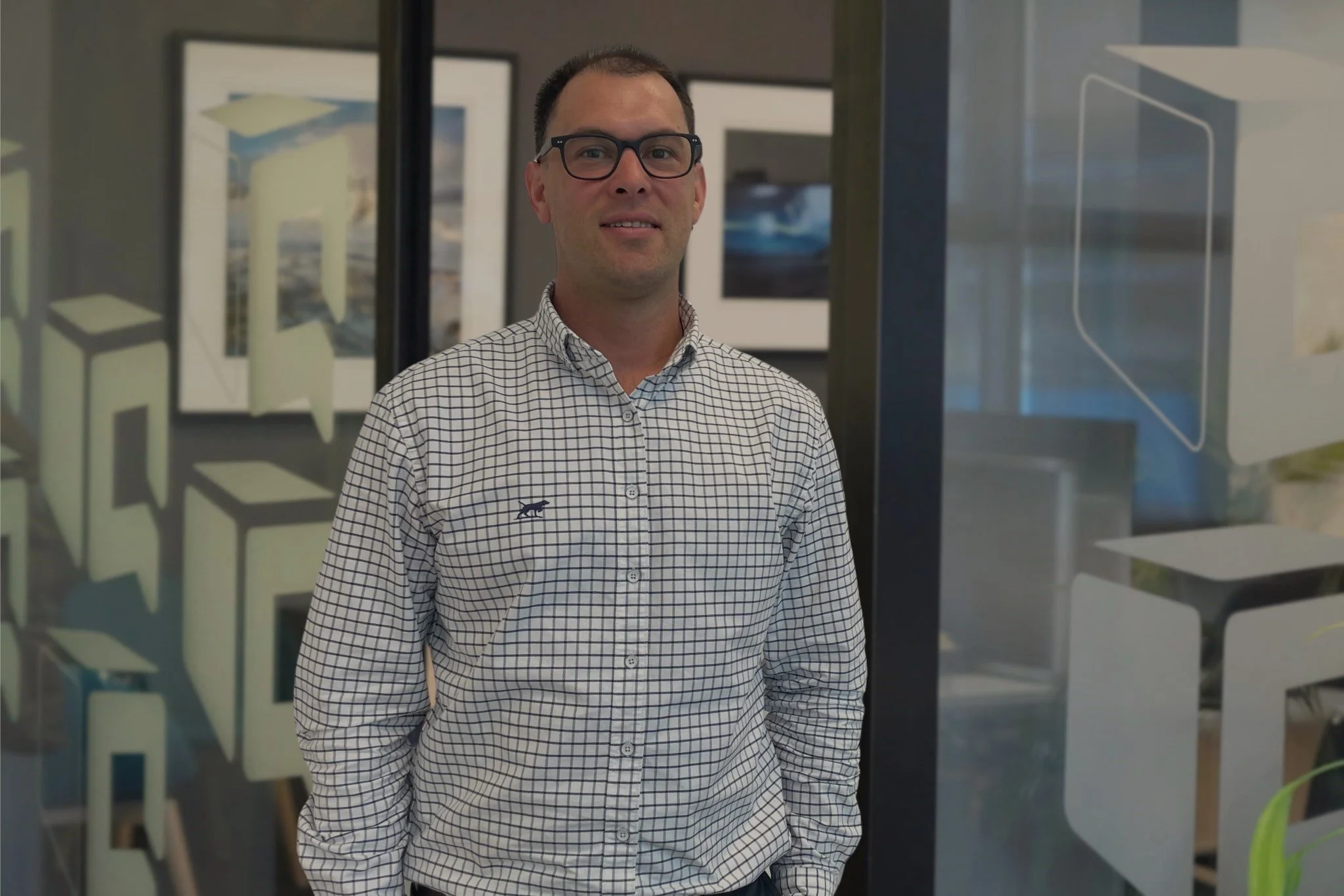 Man wearing glasses and a checkered button-down shirt standing in an art gallery