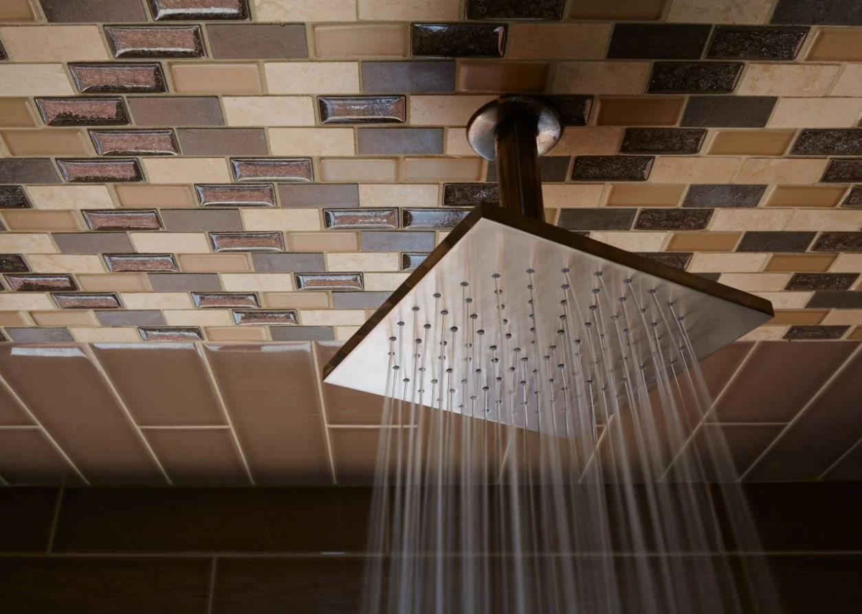 contemporary bathroom remodel featuring a ceiling-mounted rain shower with custom accent tile extending across the shower ceiling