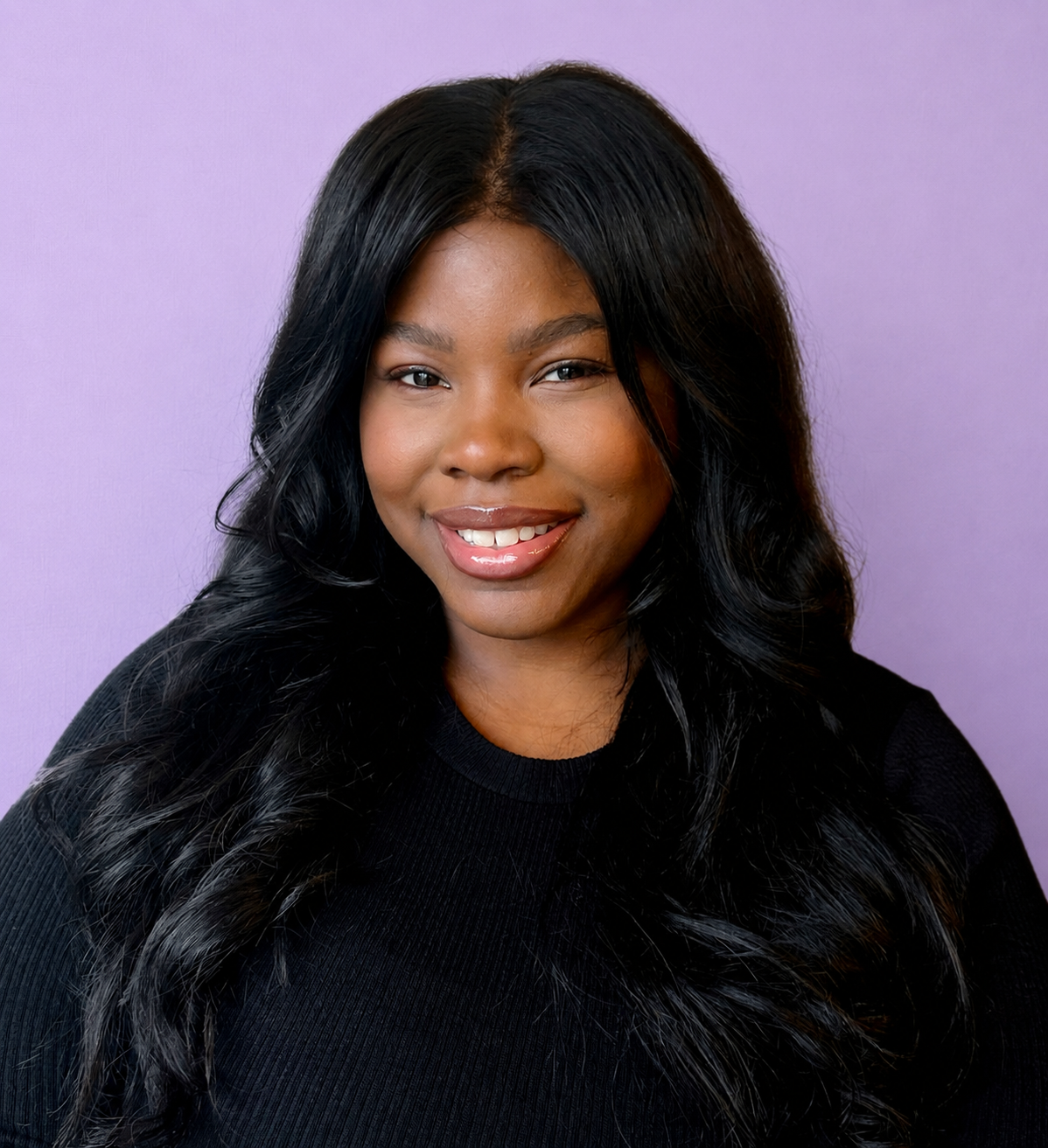 Portrait of a smiling Black woman with long black wavy hair, wearing a black top, against a light purple background.