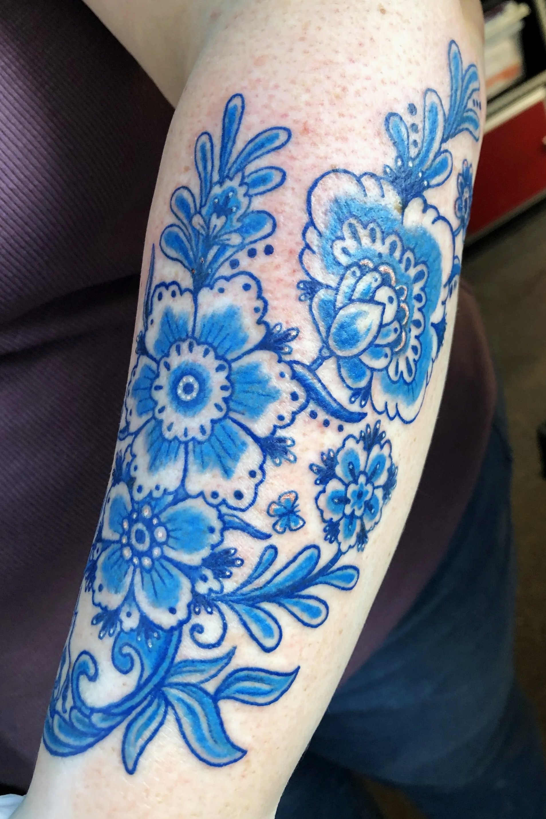 Blue floral tattoo on a person's arm.