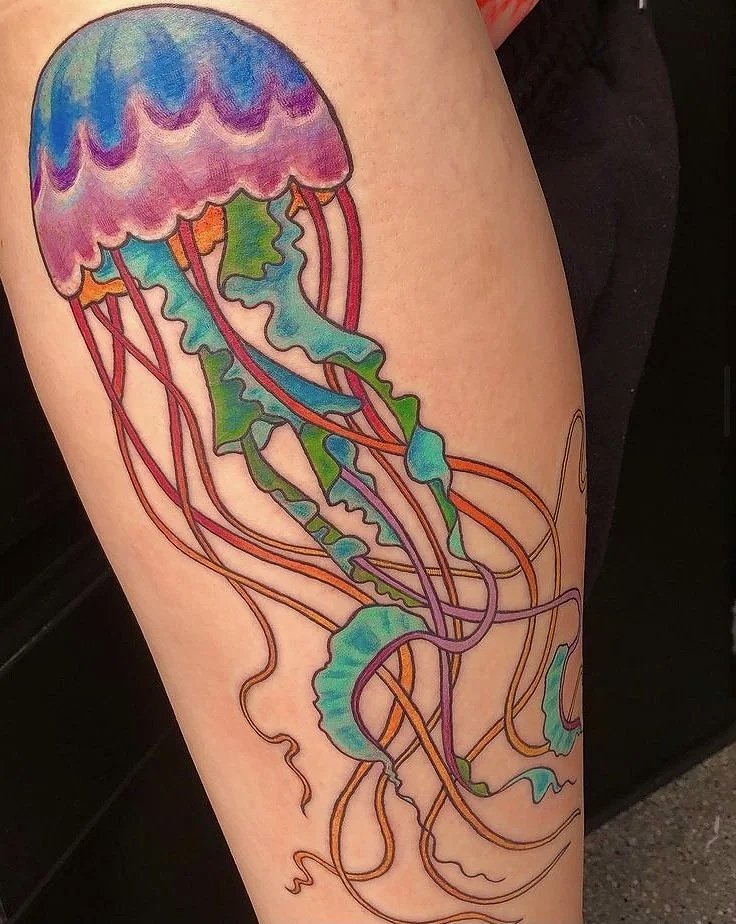 Colorful jellyfish tattoo on skin with pink, purple, blue, green, and orange colors and flowing tentacles.