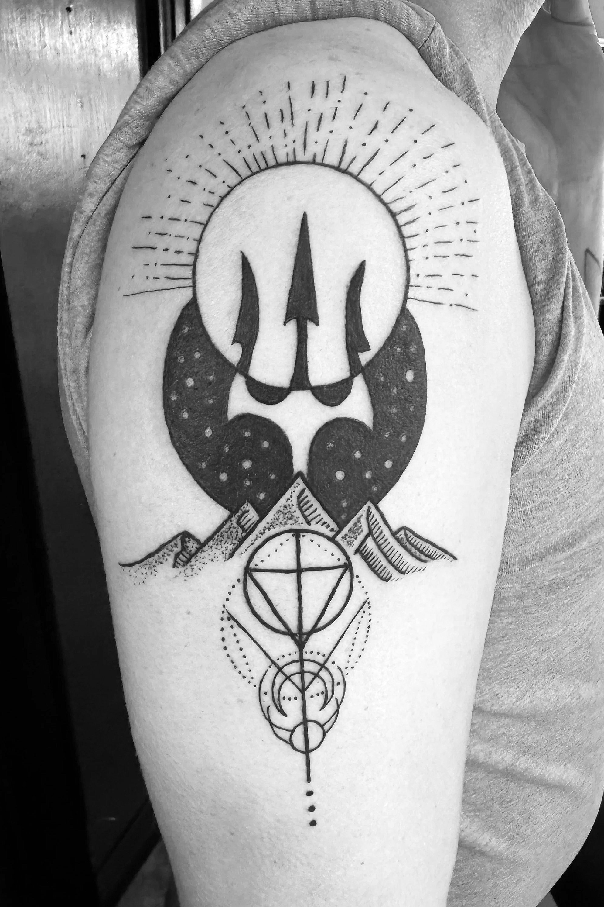 Black and white tattoo on a person's , featuring abstract geometric and symbolic elements, 