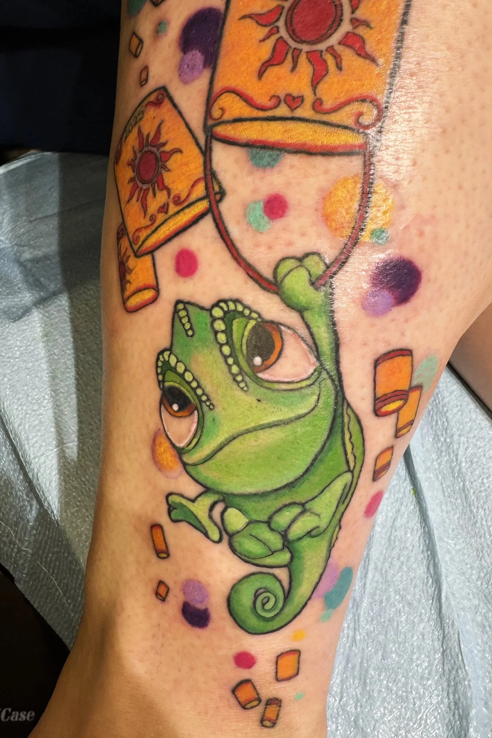 Colorful tattoo of a cartoon chameleon.