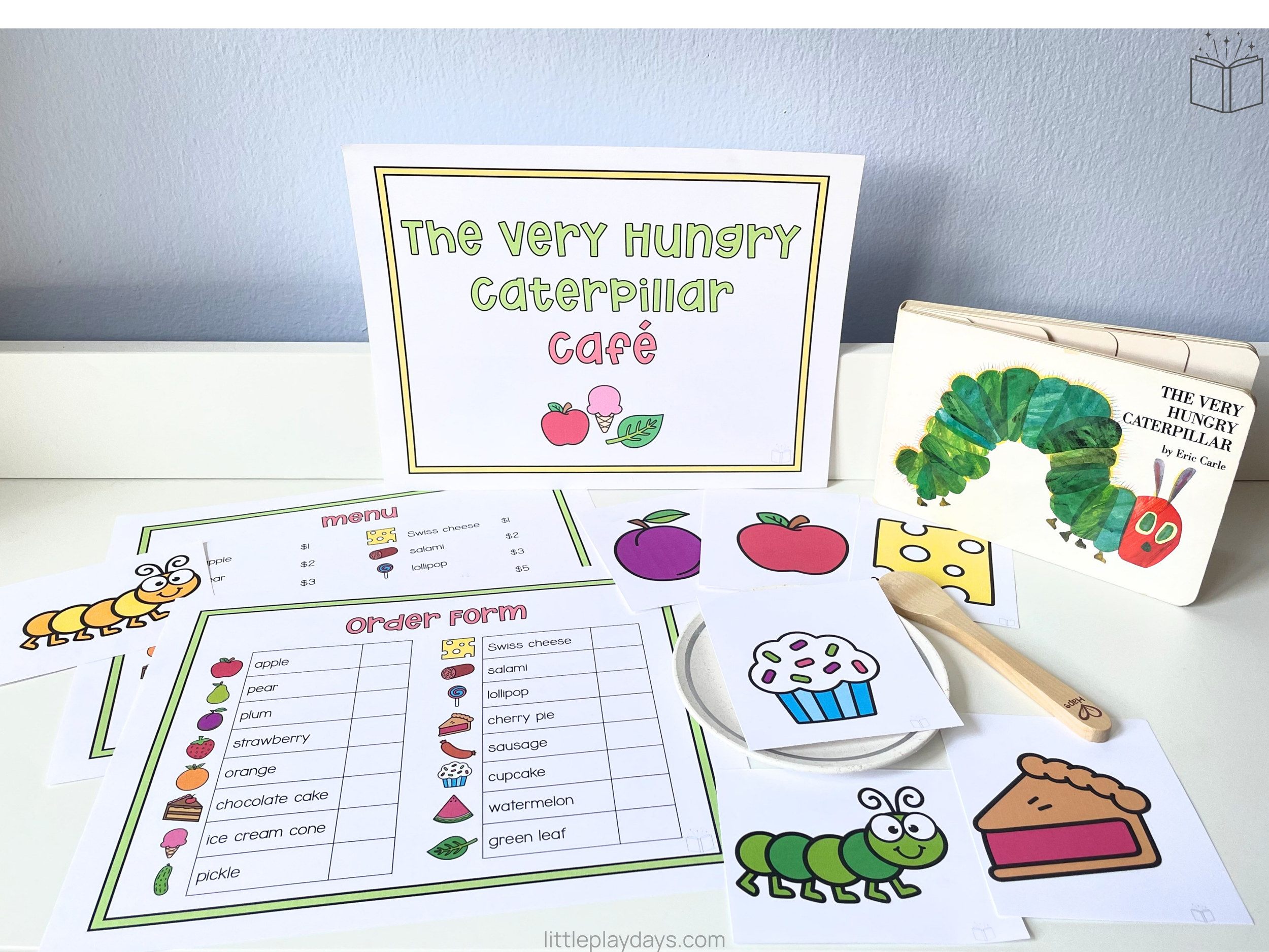 Sign for The Very Hungry Caterpillar Café with colorful border and illustrations of fruit, ice cream, and a leaf