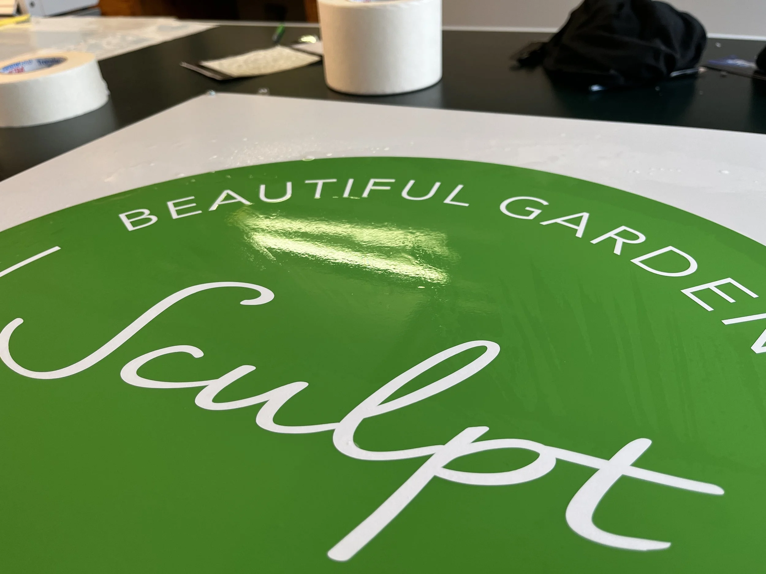 Close-up view of a green sign with white cursive text that reads 'Beautiful Garden'