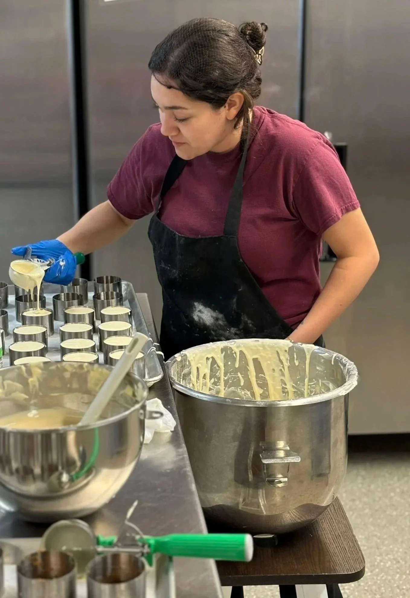 Co-owner Ariceli preparing handcrafted mini cheesecakes in a commercial kitchen using fresh ingredients and small-batch techniques