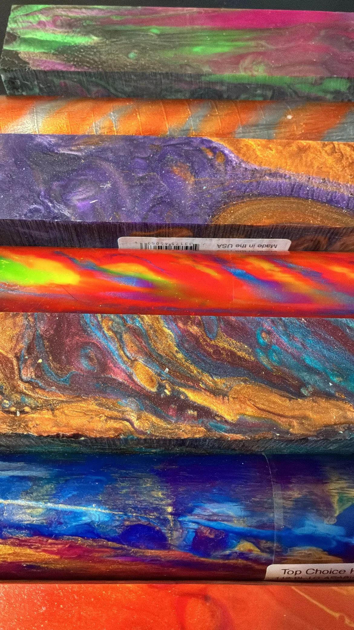 Close-up of a colorful abstract painted object or package with swirling patterns of blue, orange, purple, green, and red.