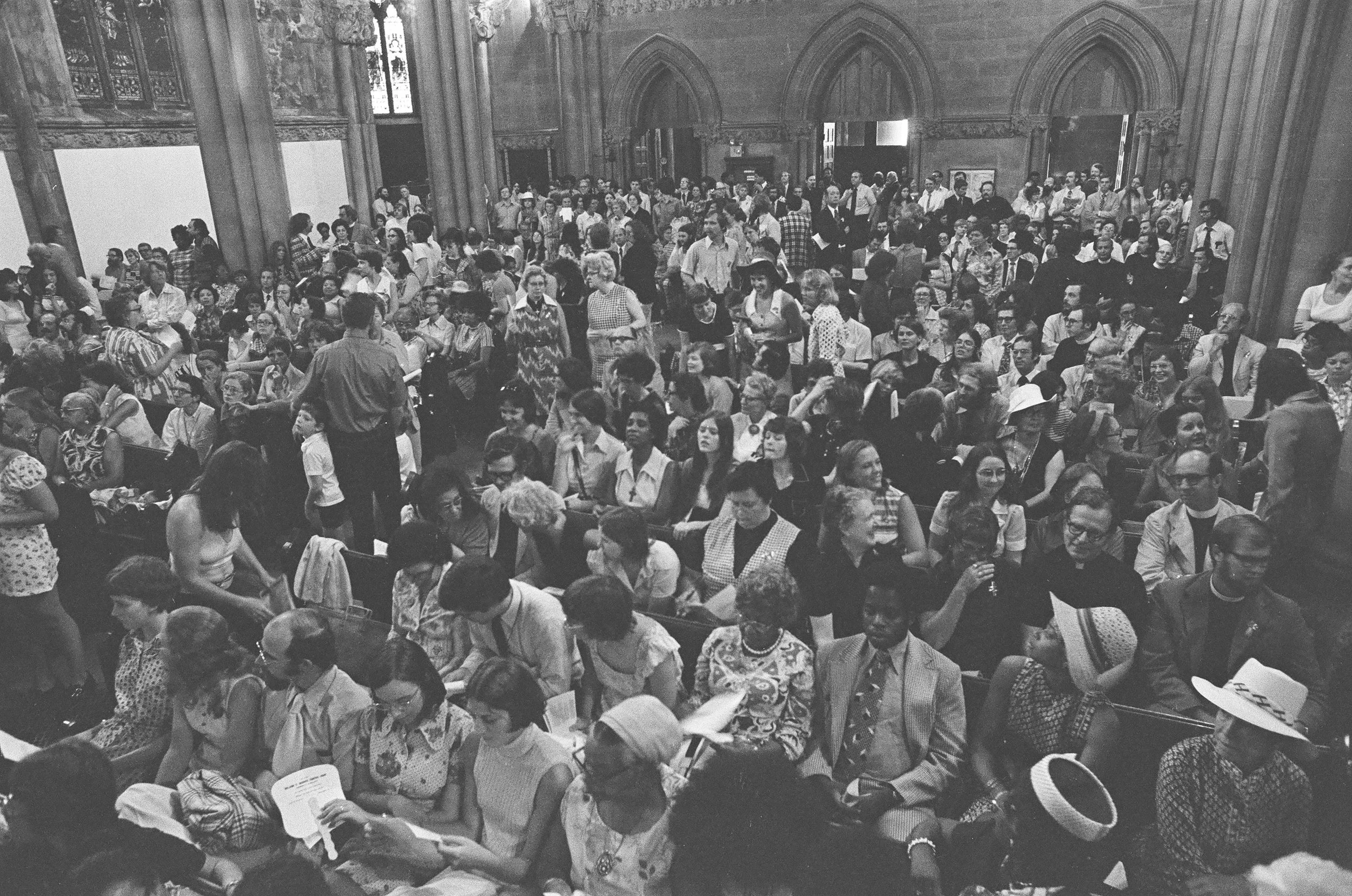 Brad Hess photograph, Church of the Advocate, Philadelphia Eleven ordinations, 1974, women priests, Episcopal, large crowd some seated and others standing, possibly attending an event or service.