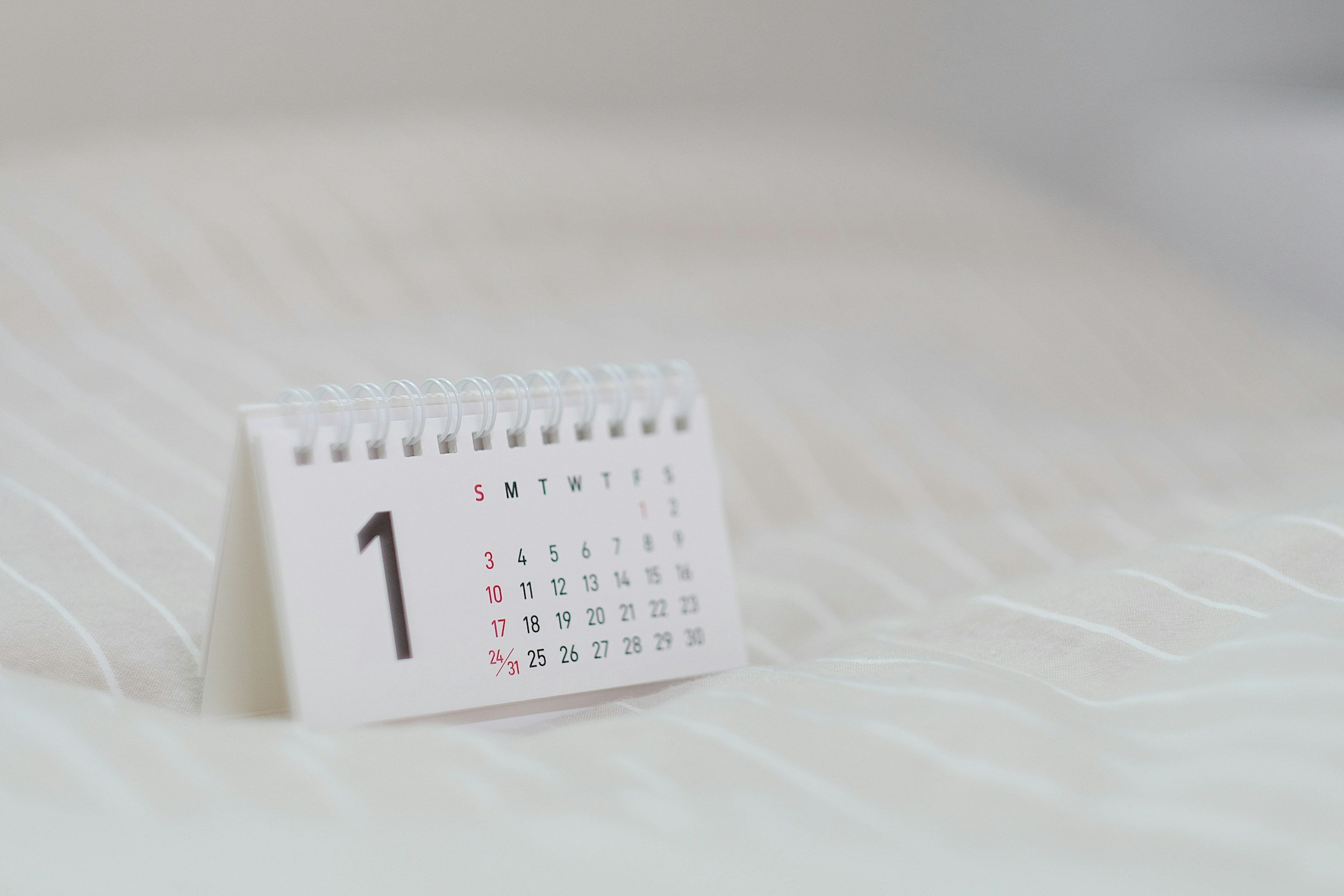 Desk calendar showing the month of January, with days and dates visible, placed on a white surface.