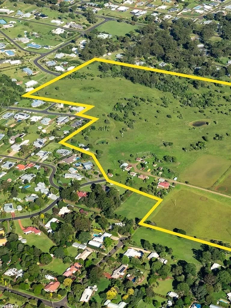 Aerial view of a suburban neighborhood with houses, streets, and a large green field outlined in yellow.