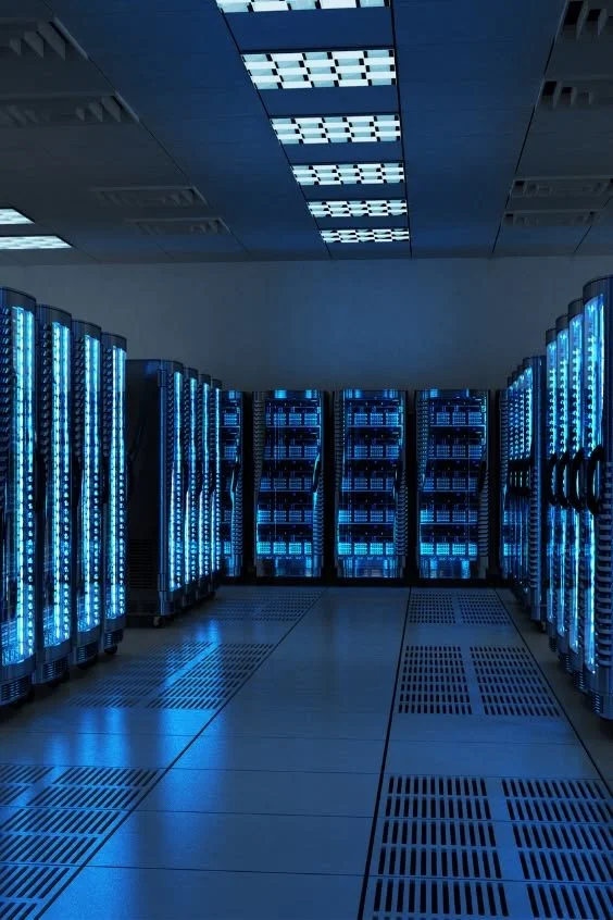 A dimly lit data center with multiple server racks illuminated by blue LED lights.