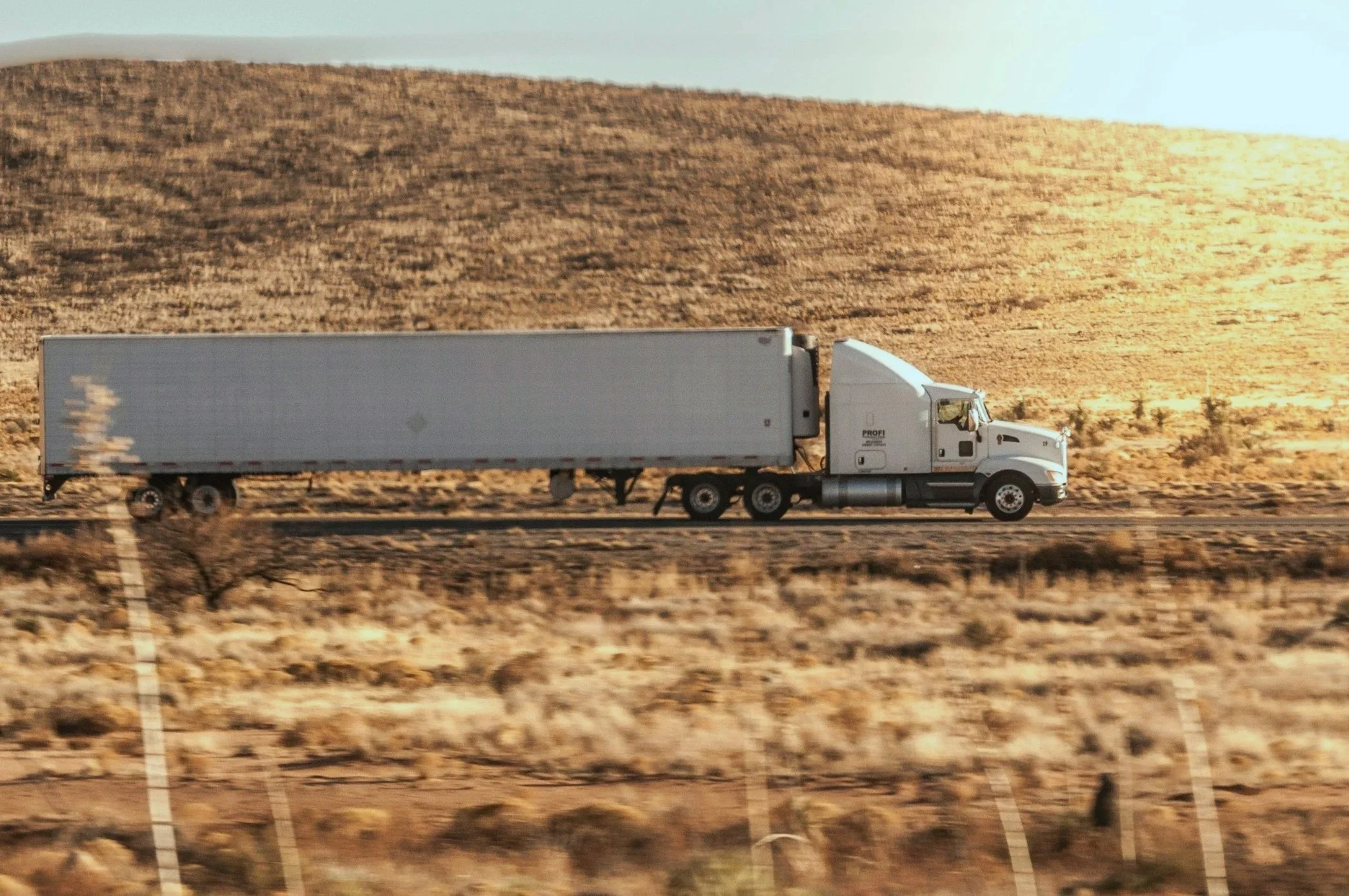A semi driving through a desert. Driver services.