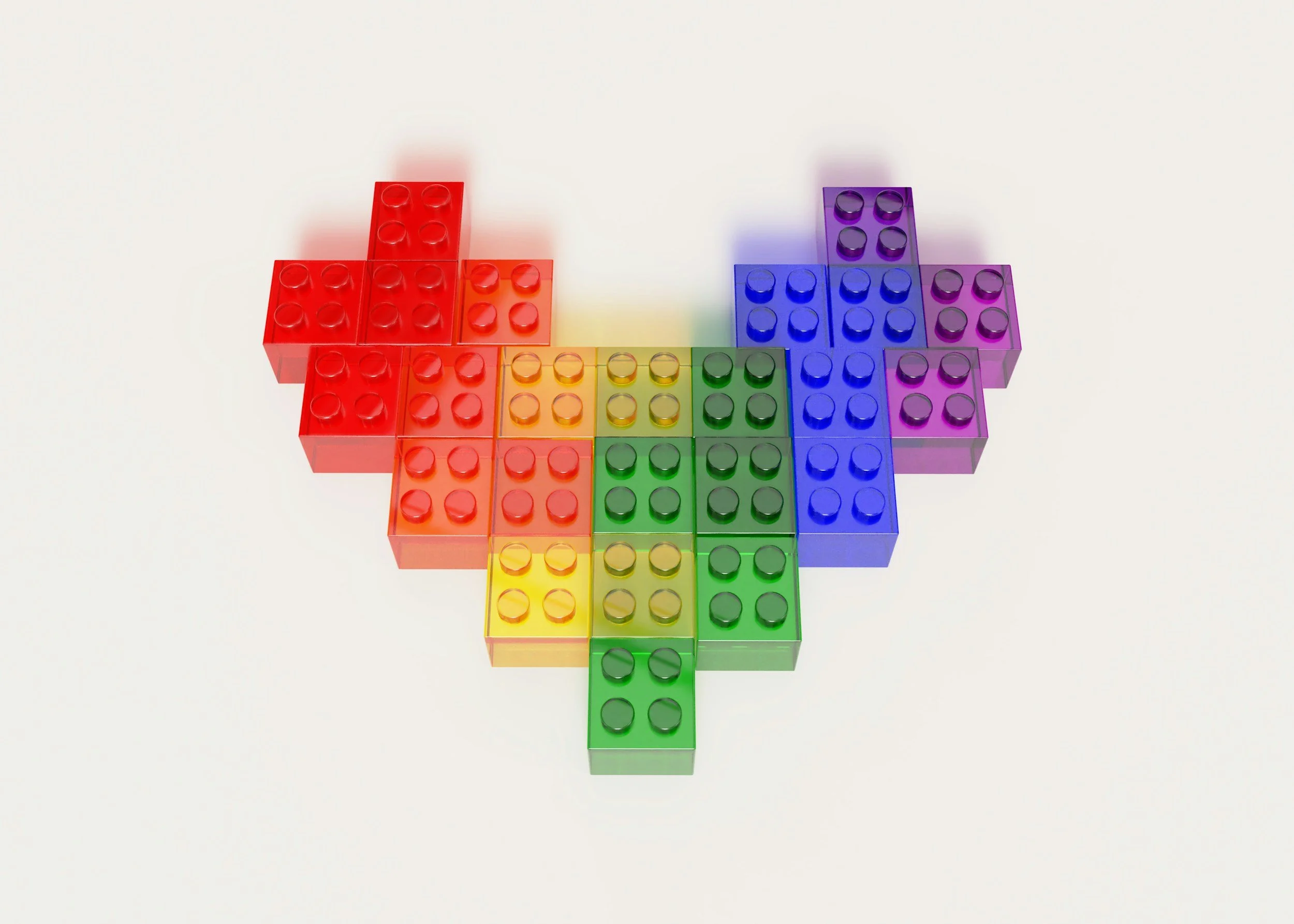 Colorful transparent building blocks arranged in a rainbow pattern on a white background.