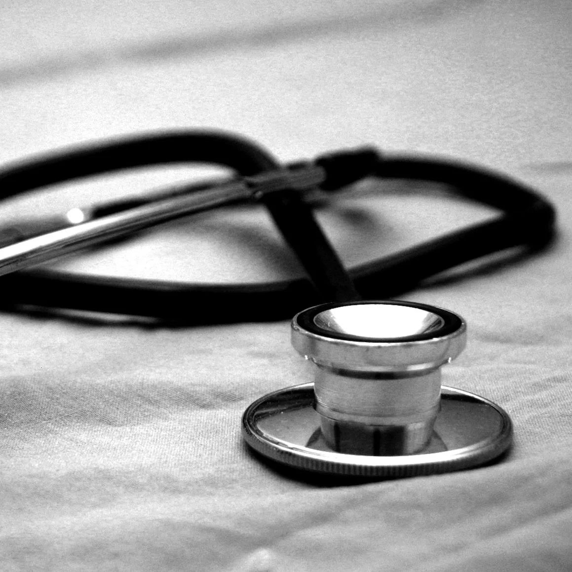 A stethoscope sits on a hospital bed
