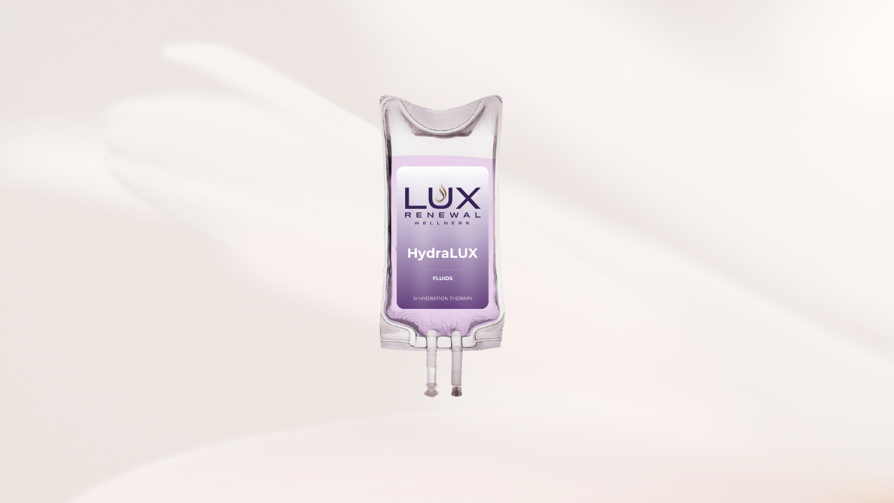 A medical IV drip containing lavender-colored fluid, labeled "LUX RENEWAL WELLNESS HydraLUX FLUIDS IV HYDRATION THERAPY," floating in a white space with light casting shadows.