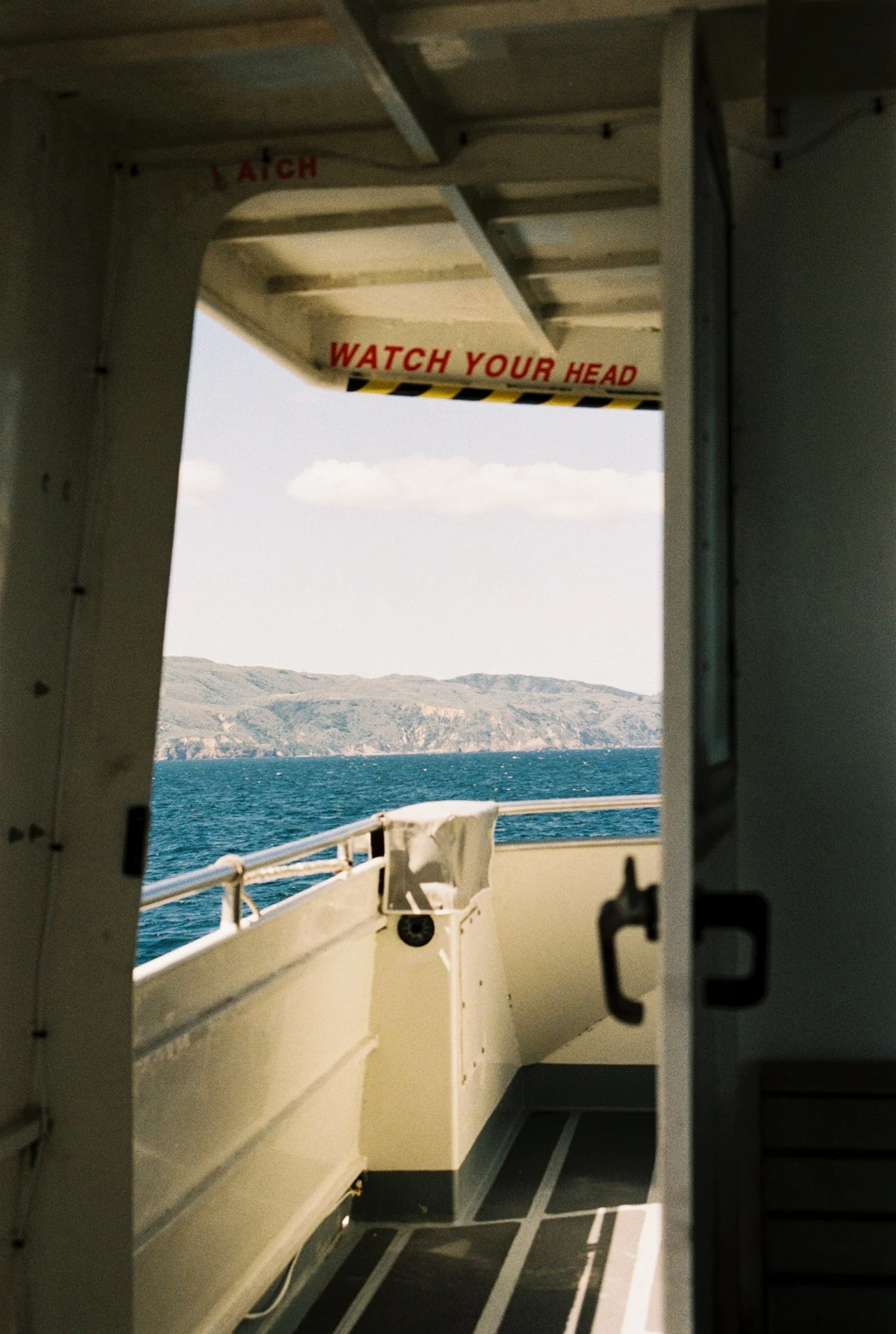 View through a boat's walkway door showing the Santa Barbara channel and a distant view of Santa Cruz Island in the background.
