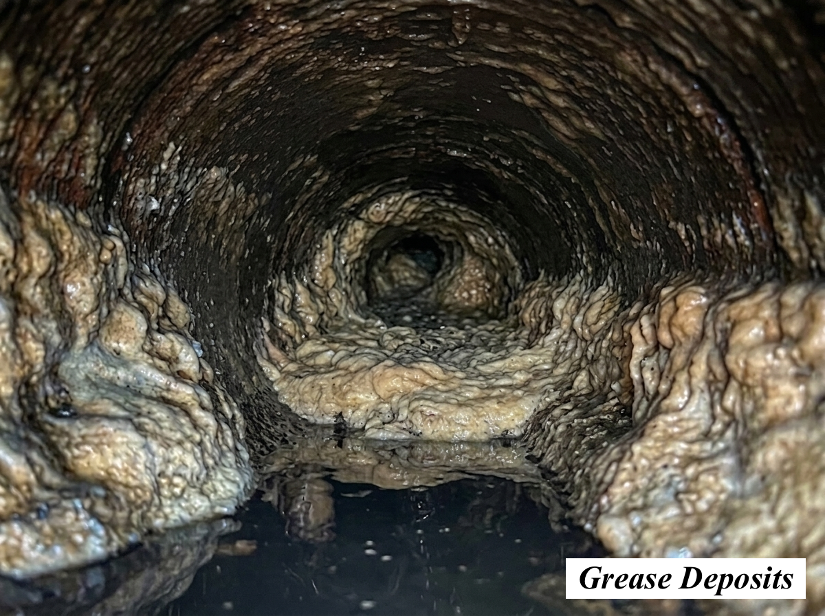 A close-up view inside a pipe showing thick grease deposits lining the walls of the pipe.