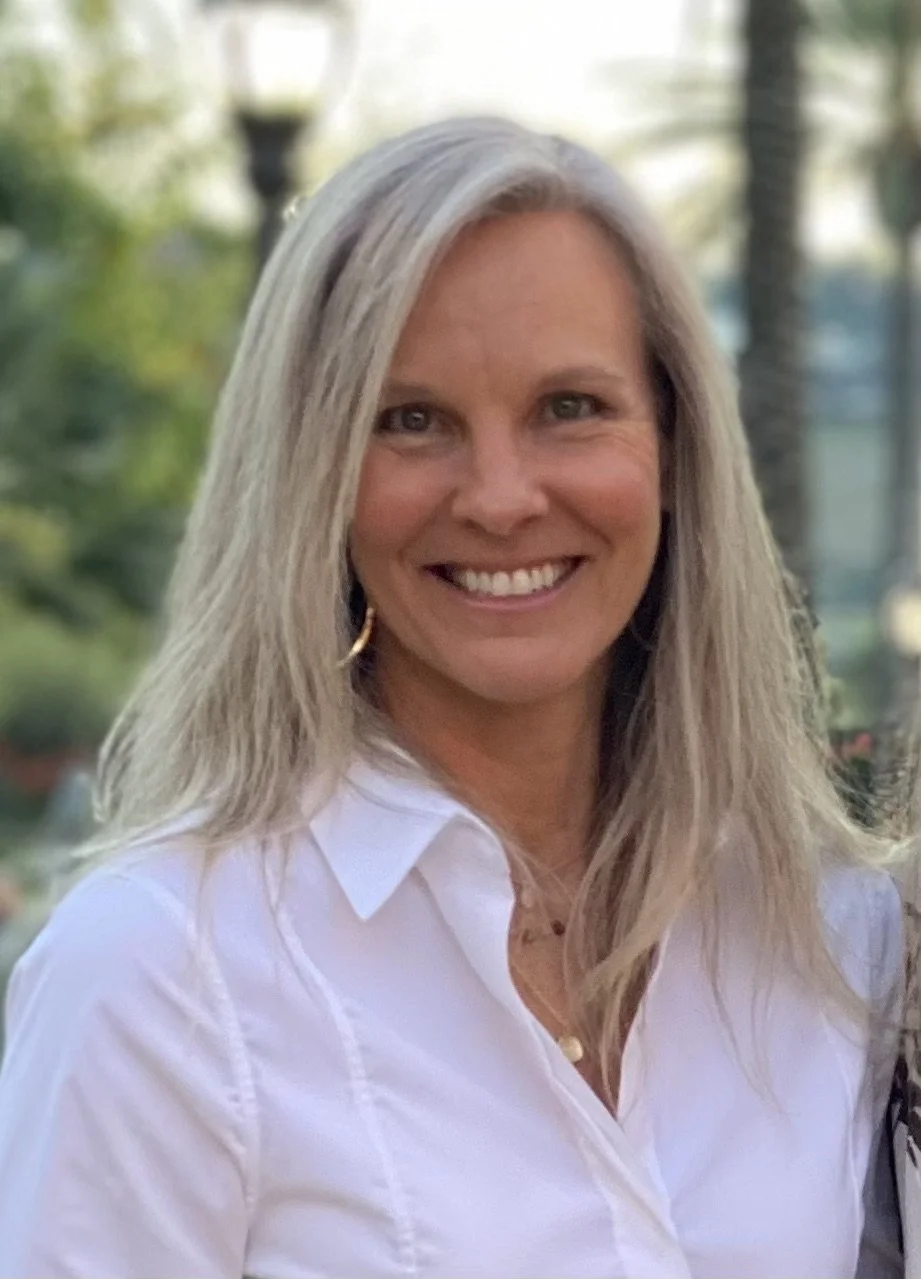 Tammy Wheeler, Lifestyle Medicine Practitioner and Menopause Coach, smiling and standing outdoors with palm trees in the background.