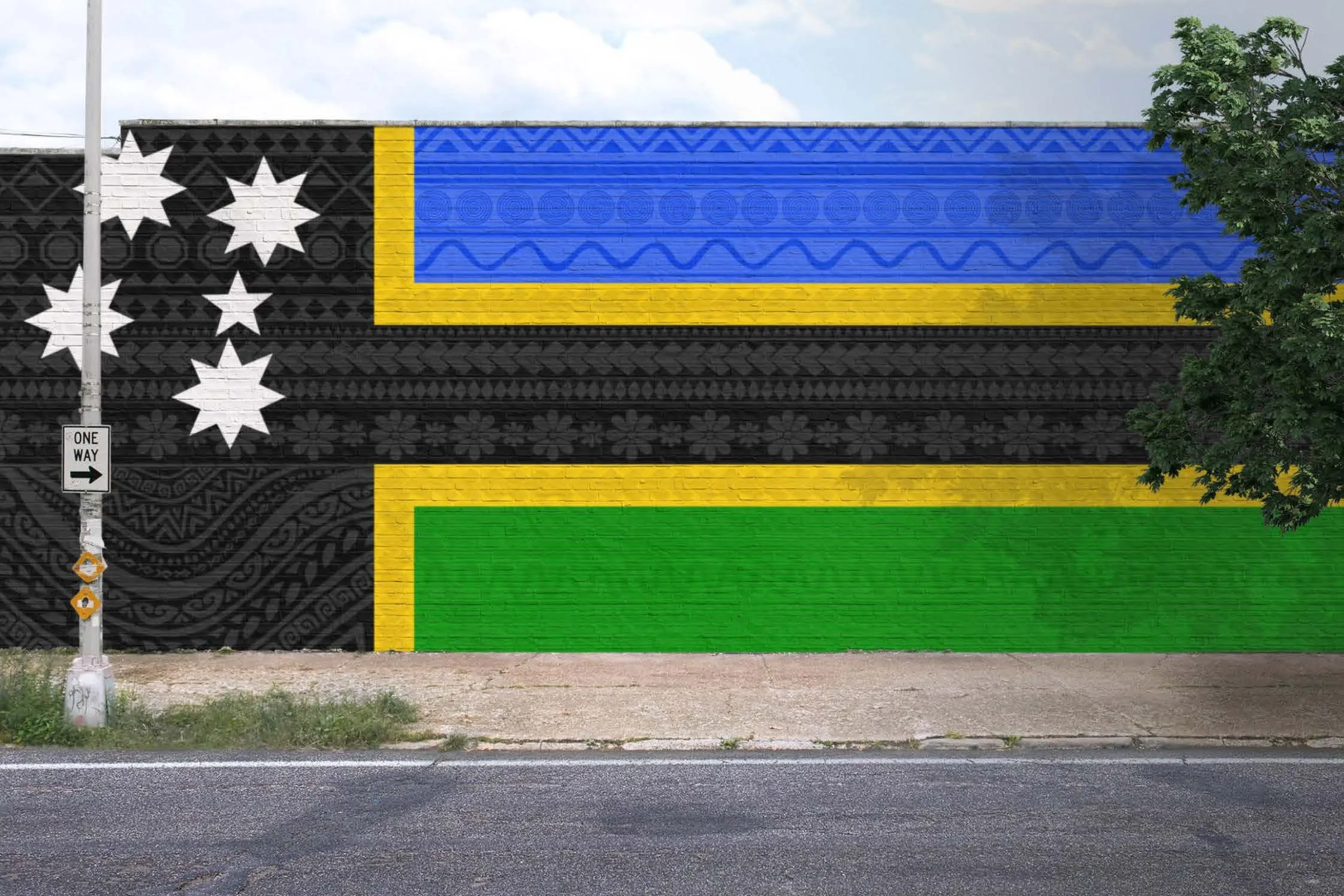 Colorful mural on a brick wall featuring geometric shapes and abstract patterns, including black, white, blue, yellow, and green sections, with a one-way street sign and a tree to the right.
