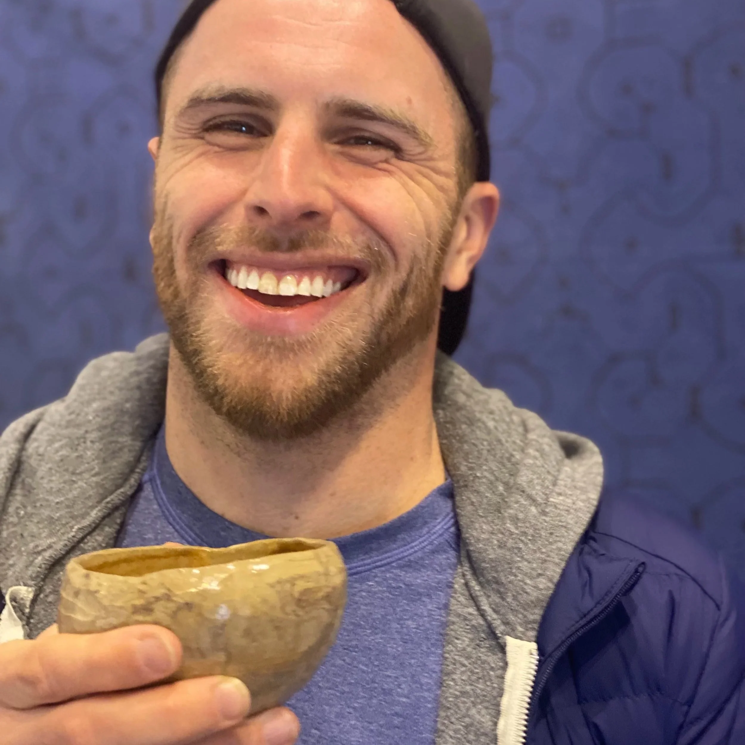 A man smiling while holding a large ice cream cone topped with sprinkles