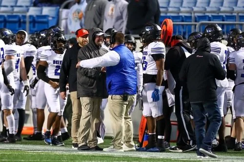 Football team and coaches gathering on the sideline during a game.
