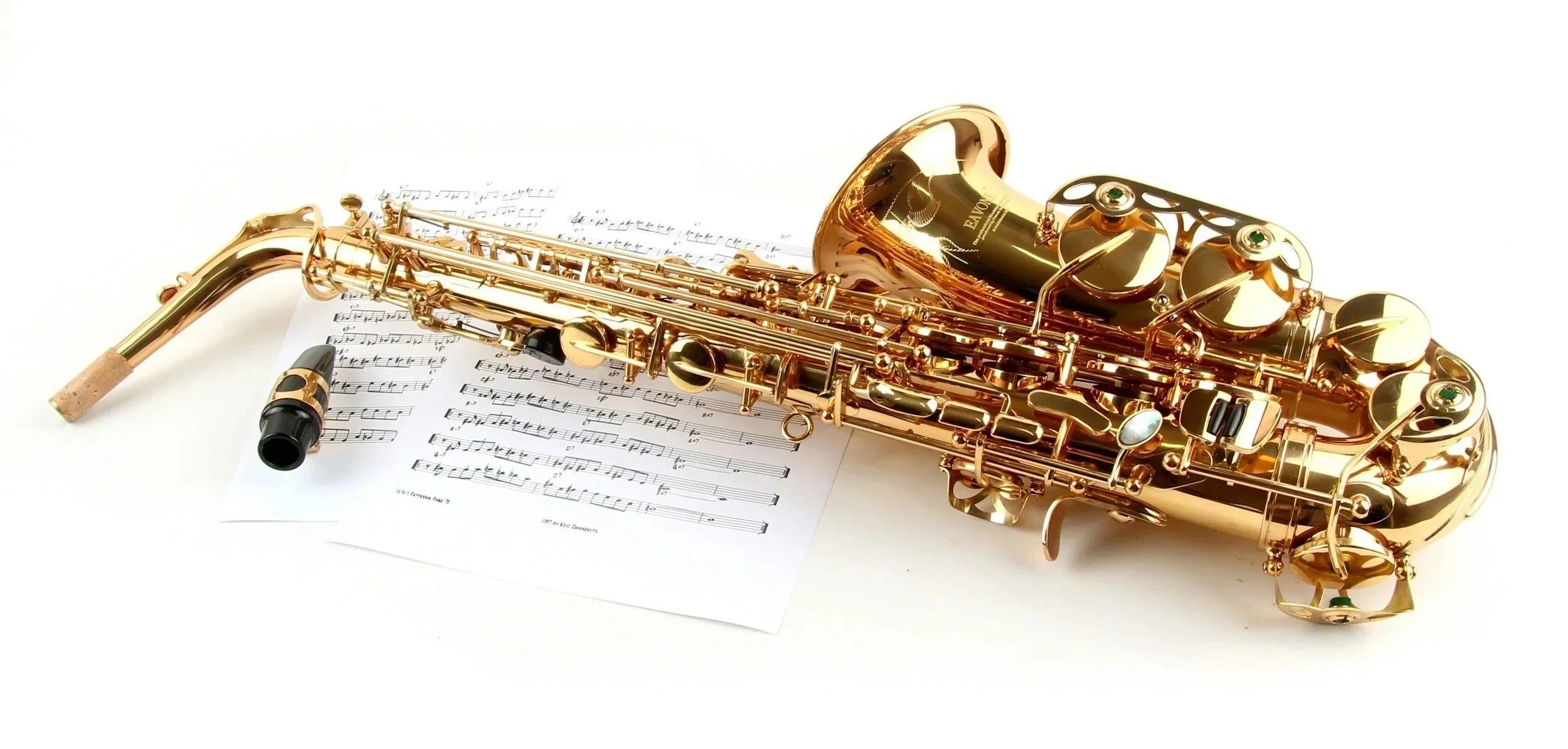 A gold-colored saxophone resting on sheet music with musical notes on a white surface.