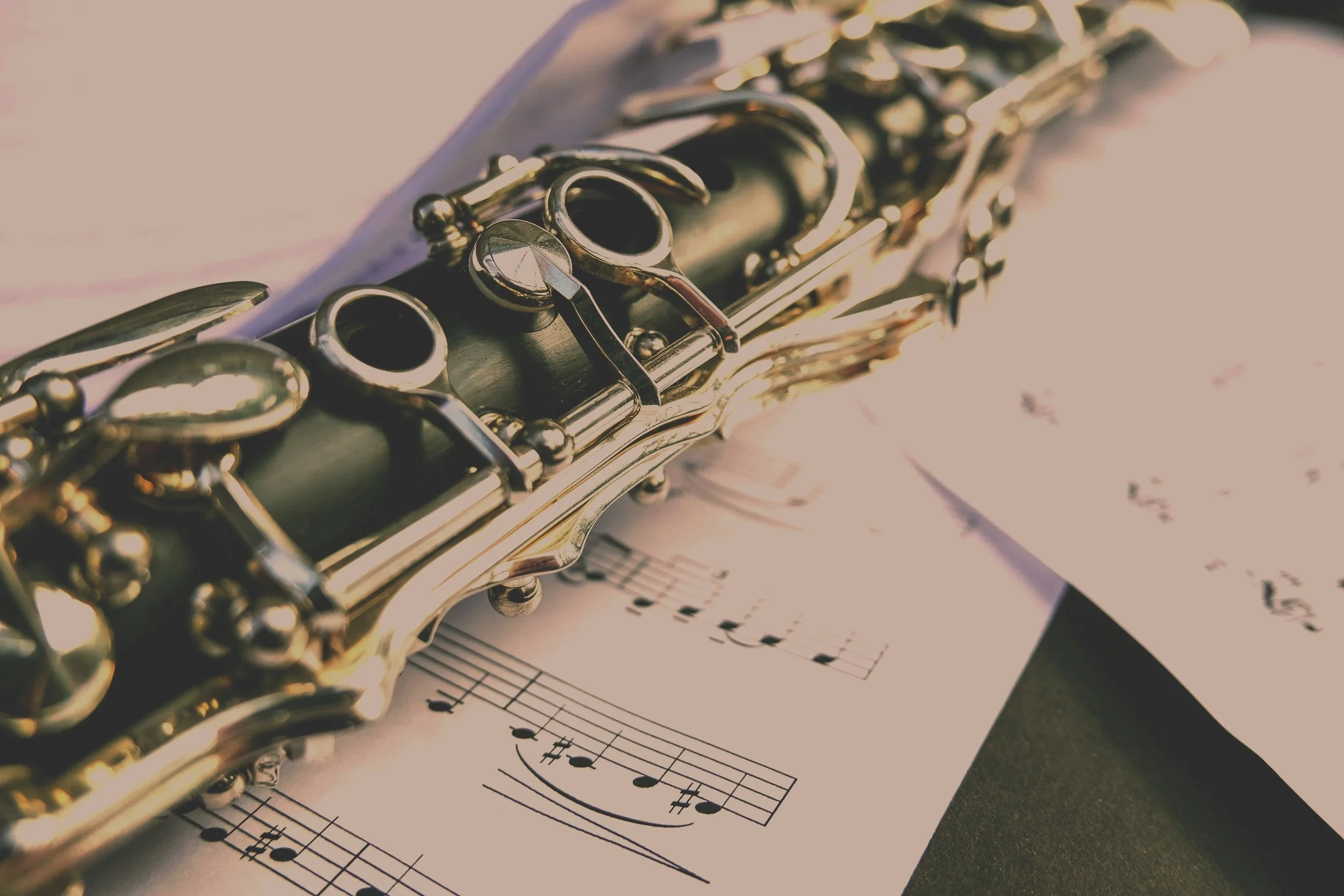 Close-up of a clarinet resting on sheet music with musical notes.