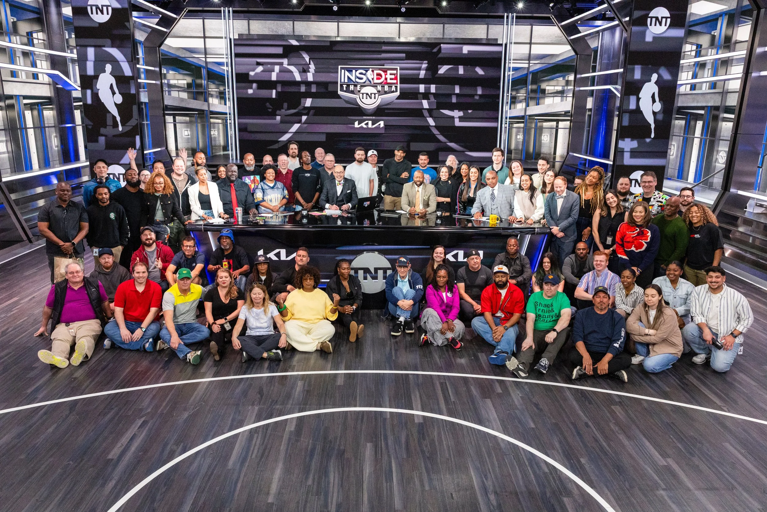 A large group of people gathered for a photo on a sports TV set with the 'Inside the NBA' logo, TNT branding, and screen displays.