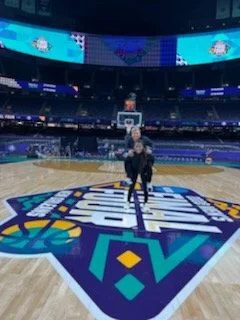 View of a basketball court inside a stadium with a person sitting on a chair at the center.