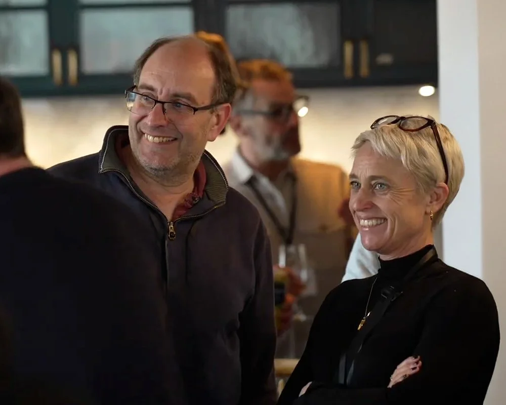 People smiling and chatting at a social gathering in an indoor setting.