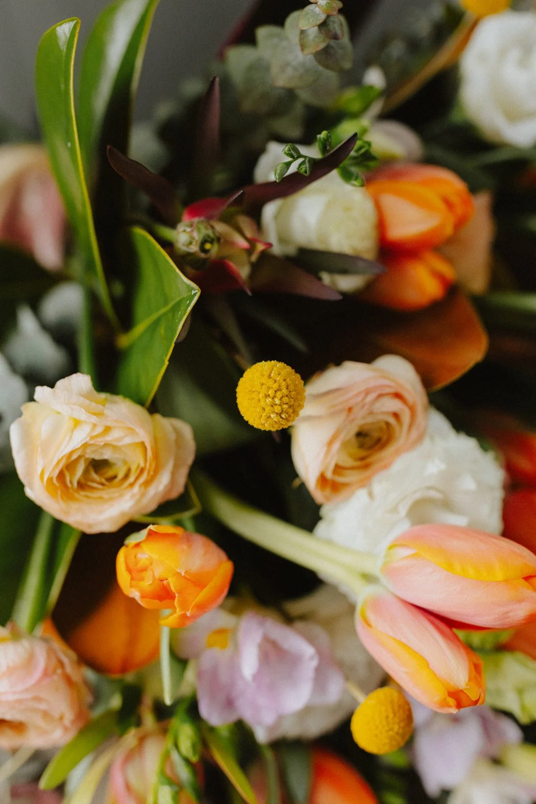 Close-up of a floral bouquet with various colored tulips, roses, and other flowers.
